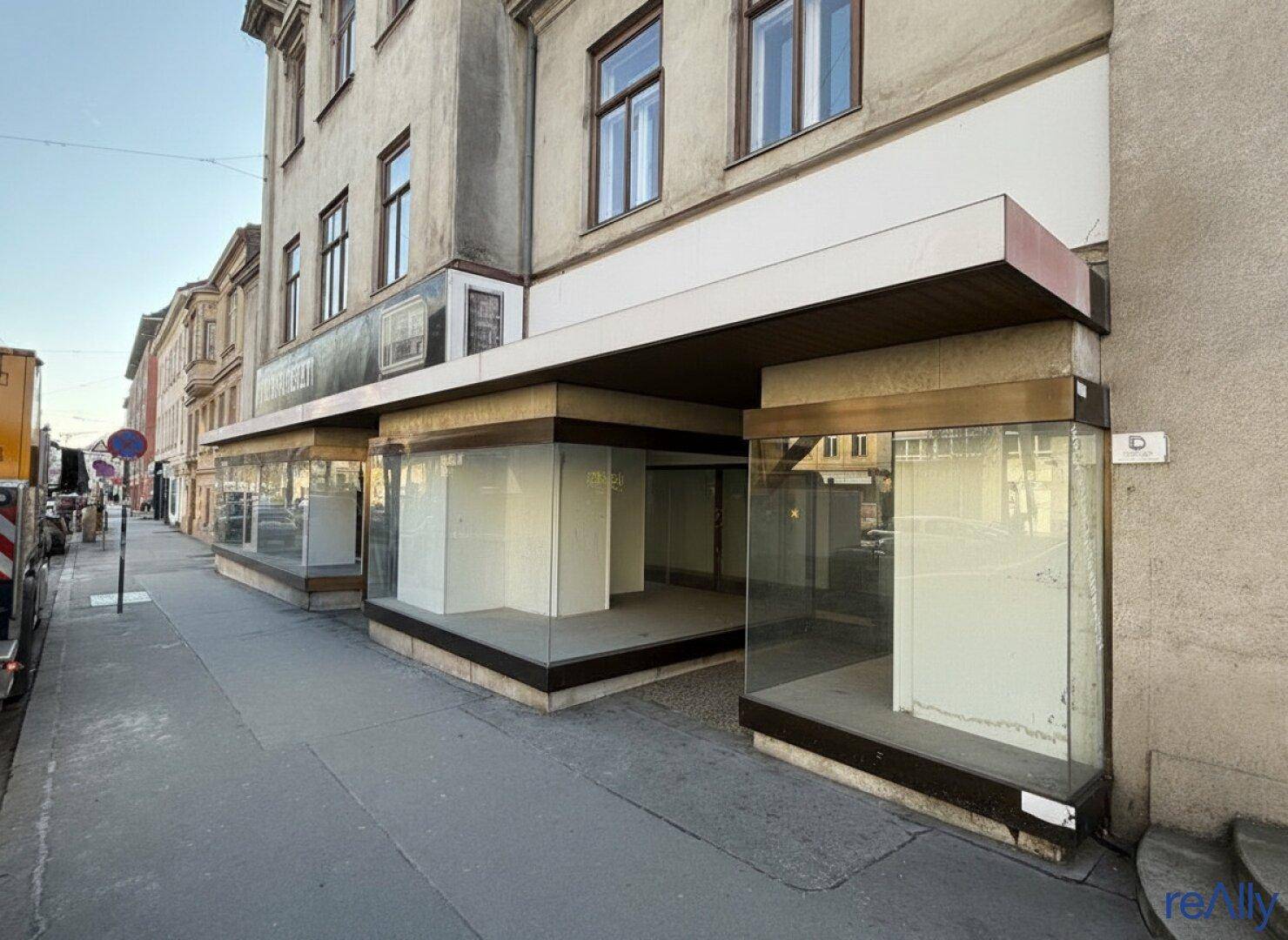 Fassade eines Geschäftsgebäudes mit großen Schaufenstern und moderner Verkleidung an der Straße.