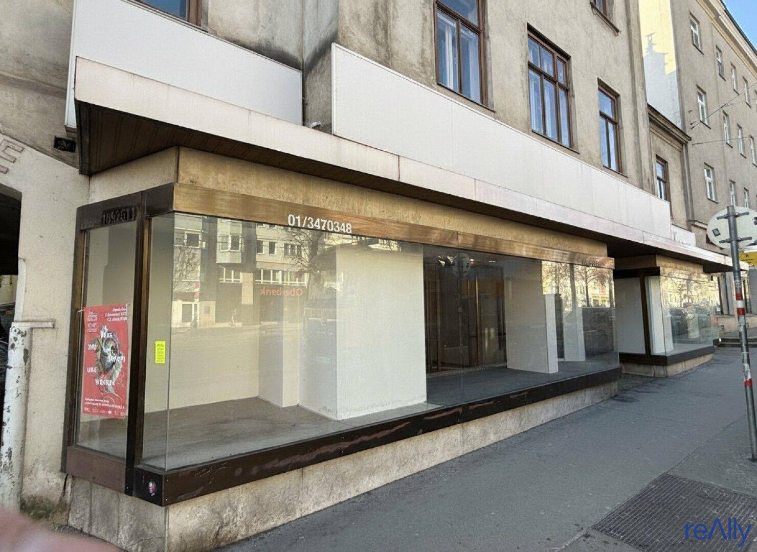 Ansicht der Geschäftsfassade mit großen Schaufenstern und reflektierenden Glasflächen an der Straße.