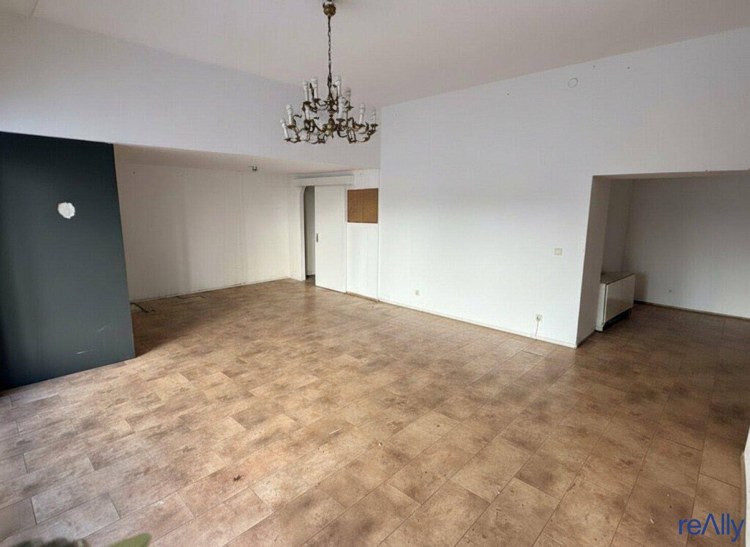 Großer, leerer Raum mit Fliesenboden und einem Kronleuchter, bereit zur individuellen Gestaltung.