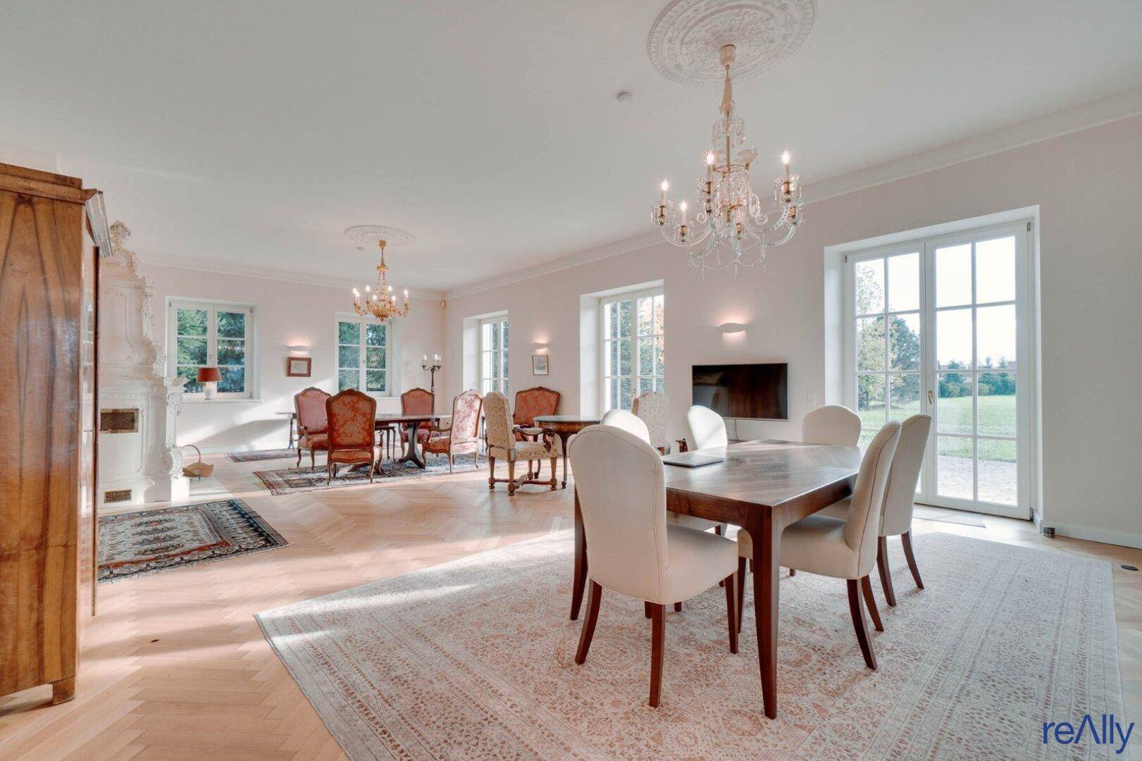 Großzügiger Wohn-Essbereich mit eleganten Möbeln, Parkettboden und Kronleuchtern.