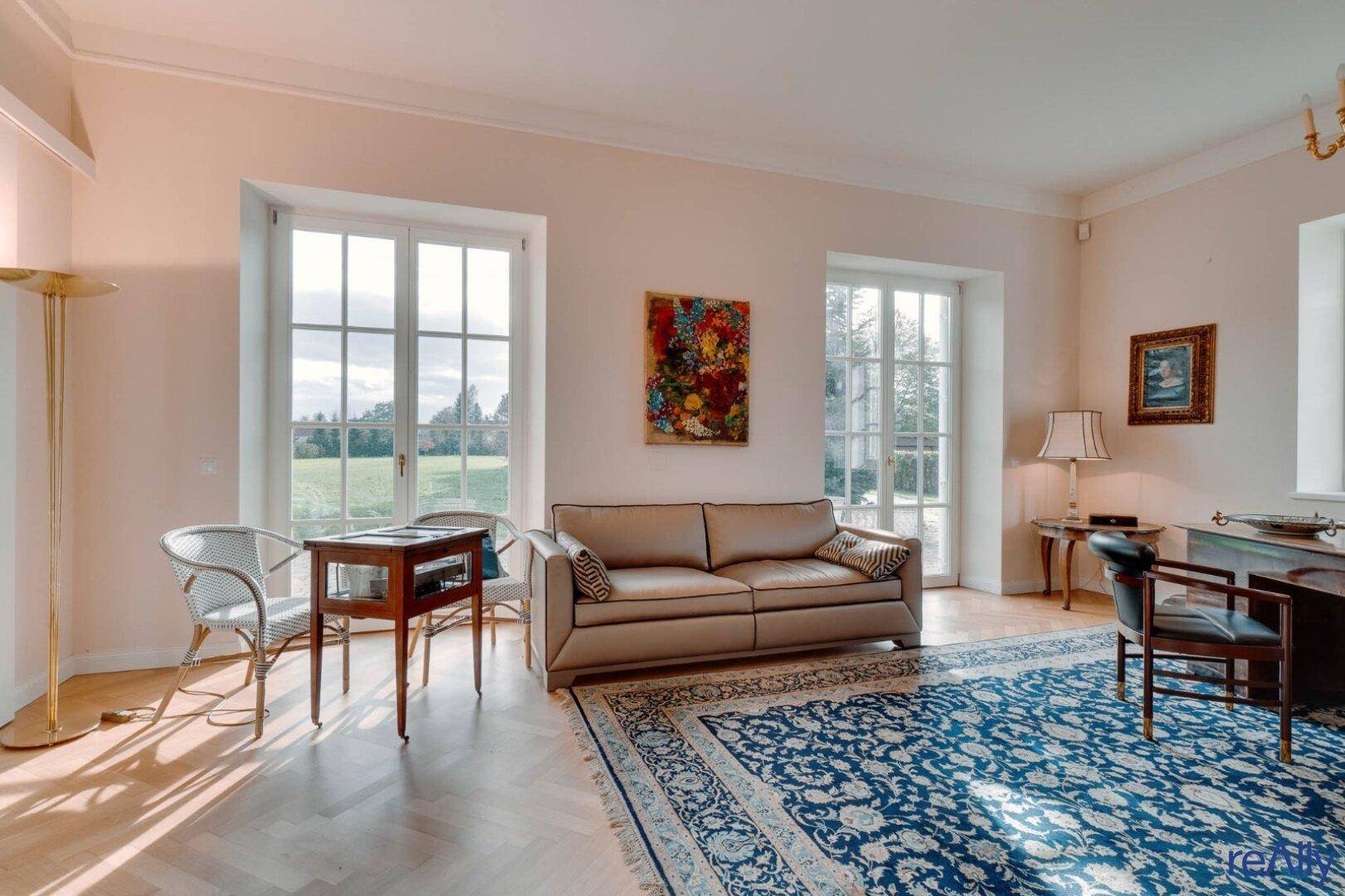 Helles Wohnzimmer mit bequemer Couch, Parkettboden und großen Fenstern zum Garten.