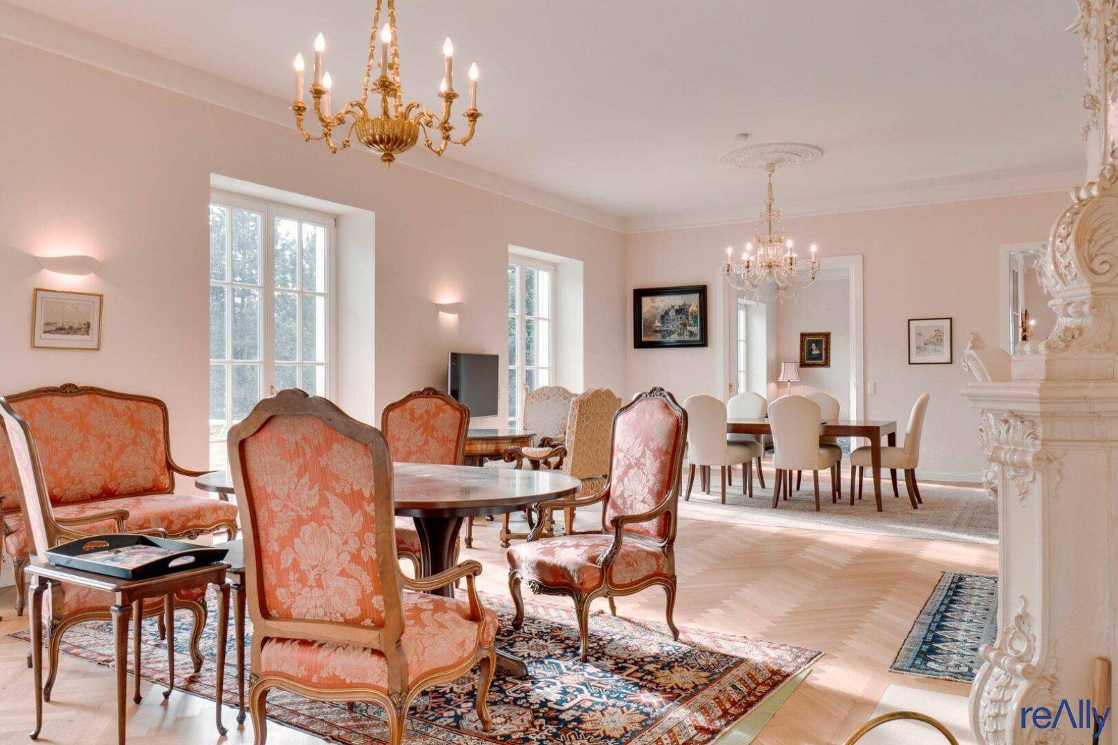 Großzügiger Wohn-Essbereich mit eleganten Sitzgelegenheiten, Parkettboden und Stuckdecke.