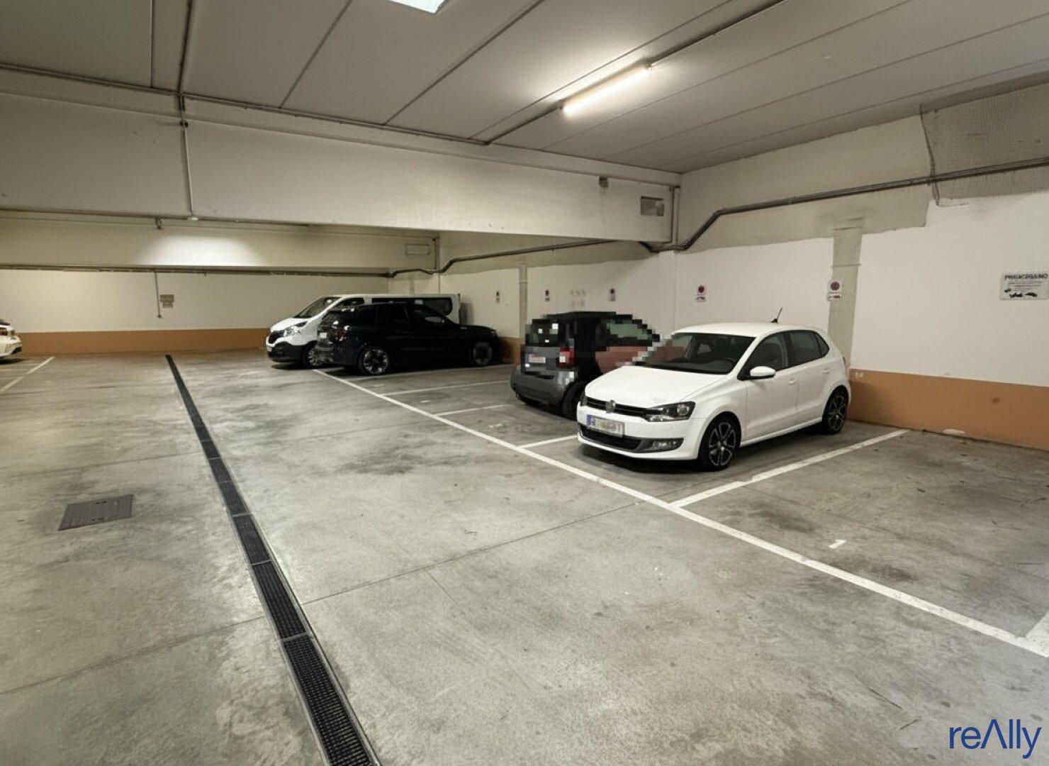 Geräumige Tiefgarage mit mehreren geparkten Autos und Betonboden.