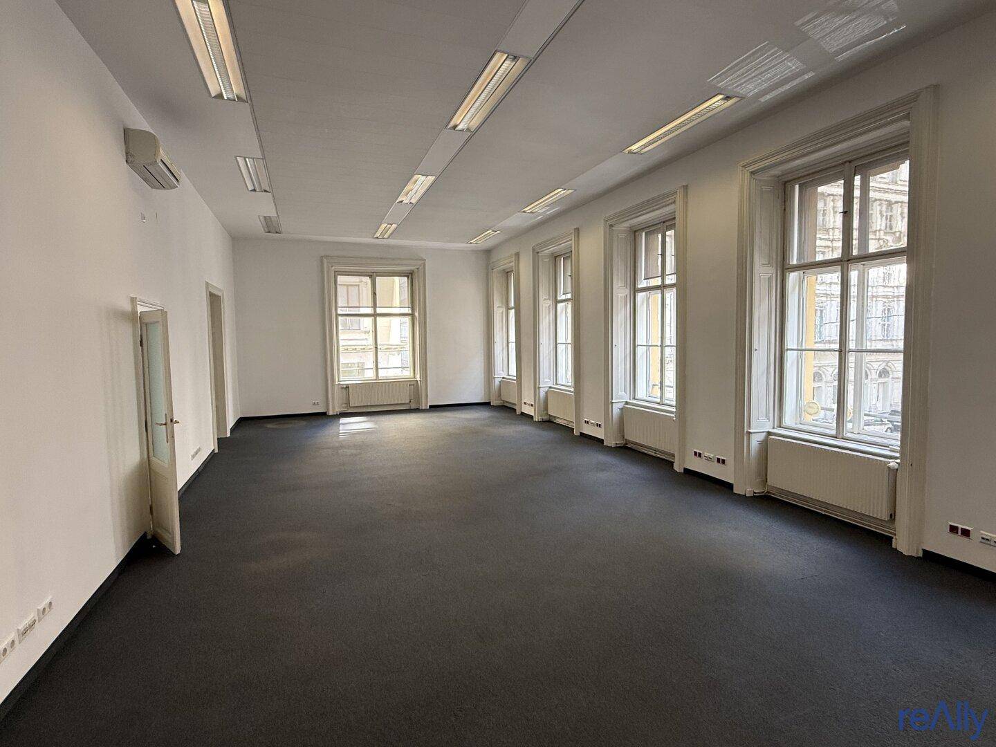 Weitläufiger Bürobereich mit vielen Fenstern, Teppichboden und integrierter Klimaanlage.