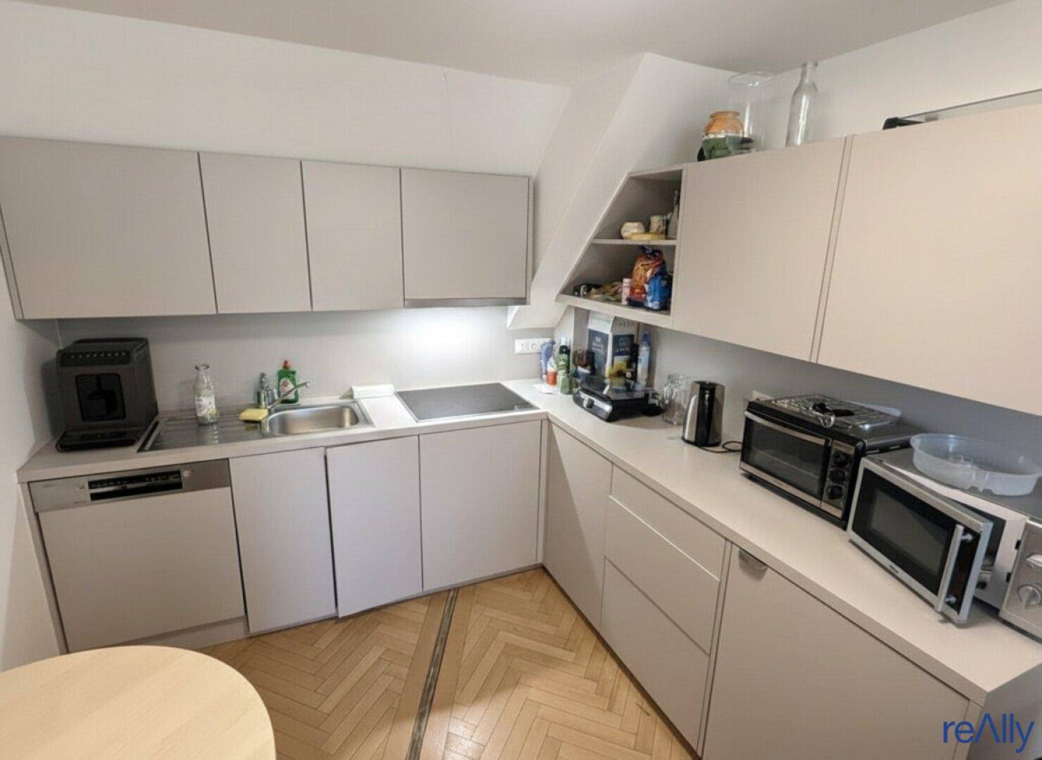 Moderne Einbauküche in Grau mit integrierten Geräten und praktischer Arbeitsfläche.