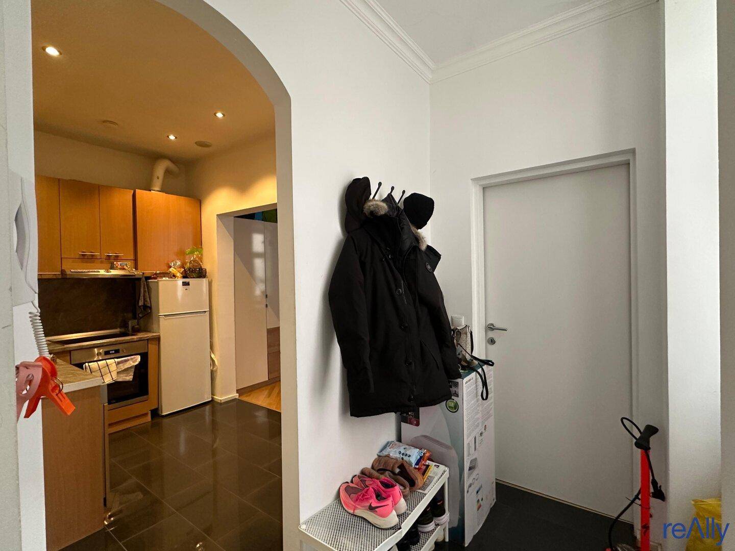 Eingangsbereich mit Garderobe und Blick in die angrenzende Küche.
