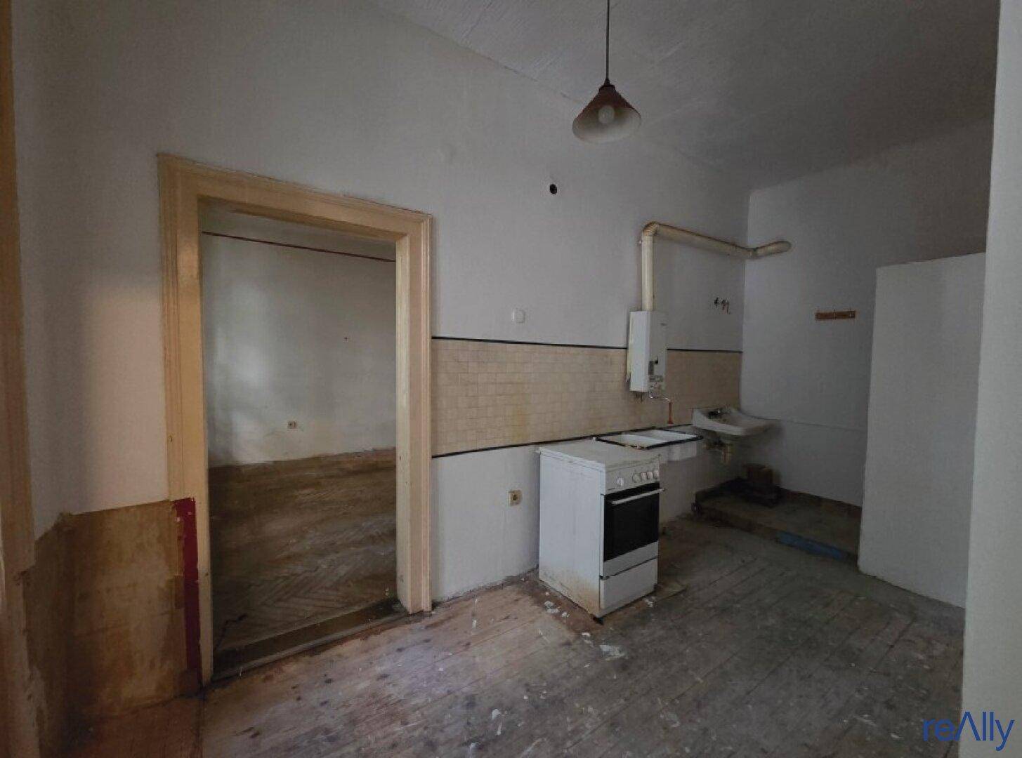 Renovierungsbedürftige Küche mit altem Herd, Spülbecken und Fliesenwand, bereit zur Sanierung.