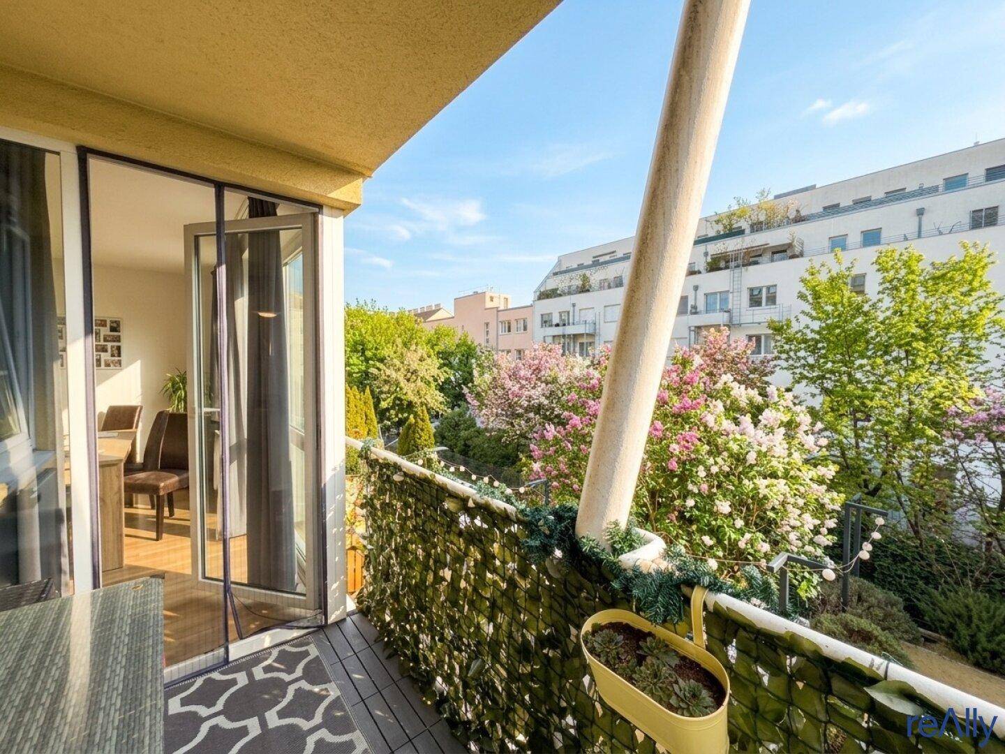 Balkon mit Blick ins Grüne, ausgestattet mit Sichtschutz und Sitzgelegenheiten.