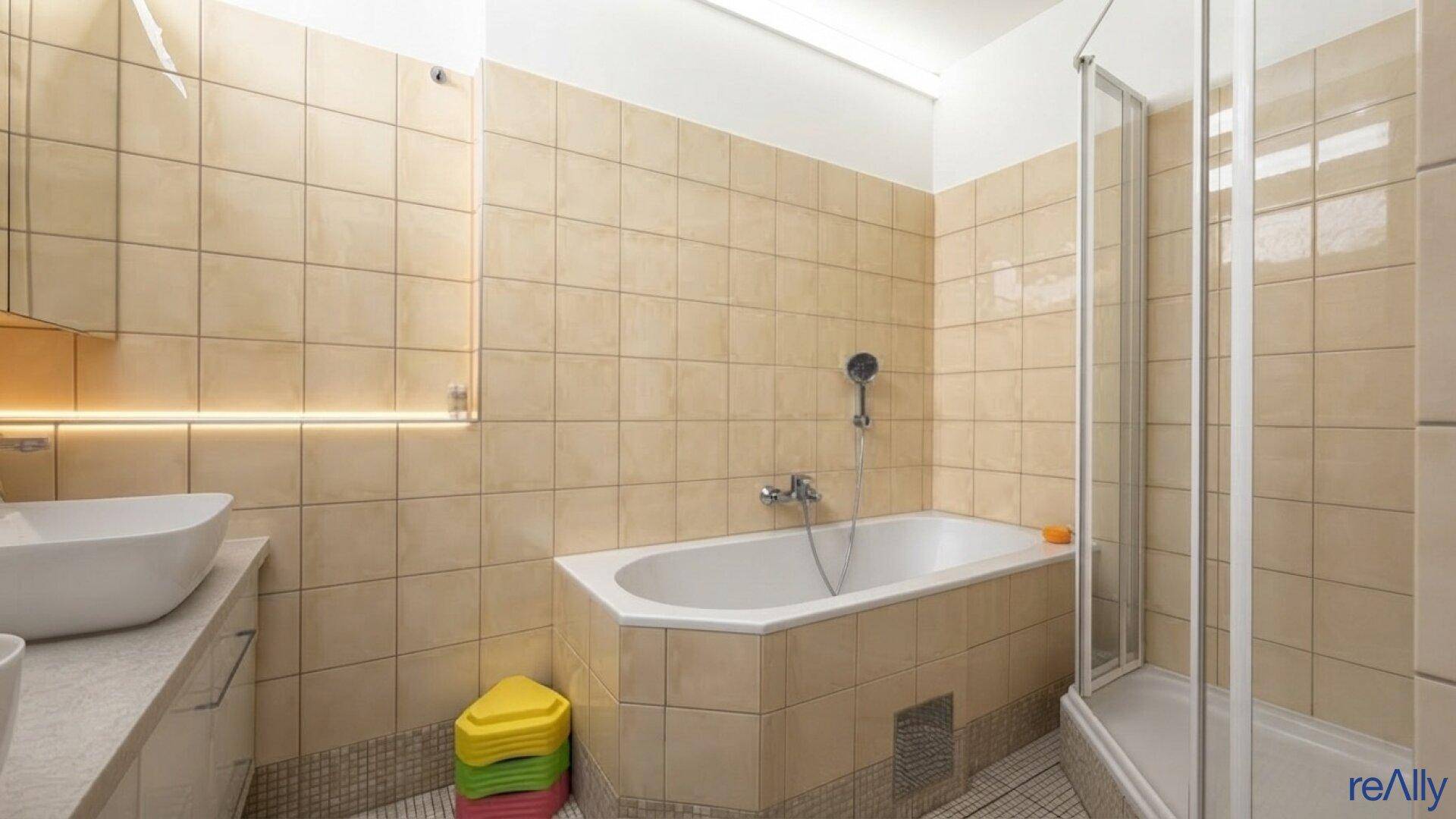 Badezimmer mit beigefarbenen Fliesen, Badewanne und separater Duschkabine.