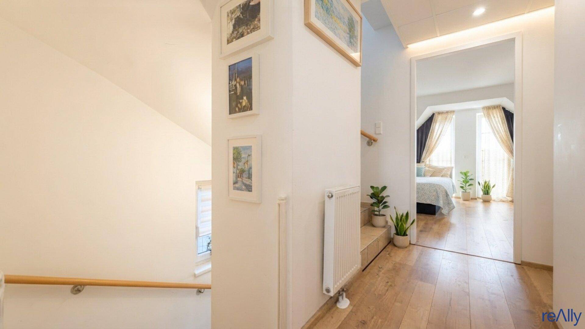Heller Flur mit Holzboden und Zugang zu einem gemütlichen Schlafzimmer.
