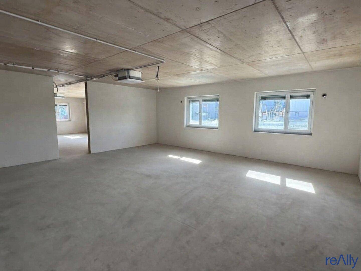 Großer, unfertiger Raum mit Betonboden und -decke, bereit für den Innenausbau.