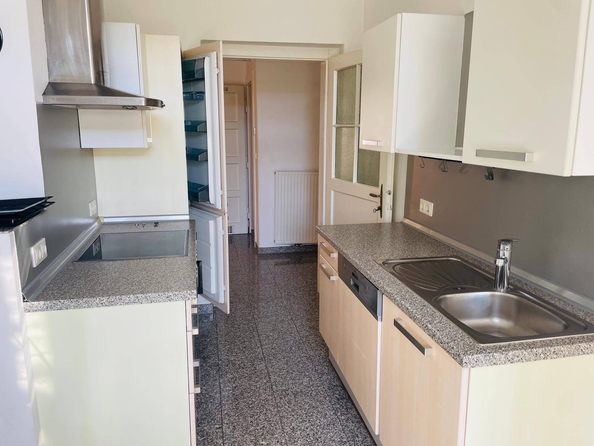 Funktionale Küche mit integriertem Kühlschrank, Geschirrspüler und Granit-Arbeitsplatte.