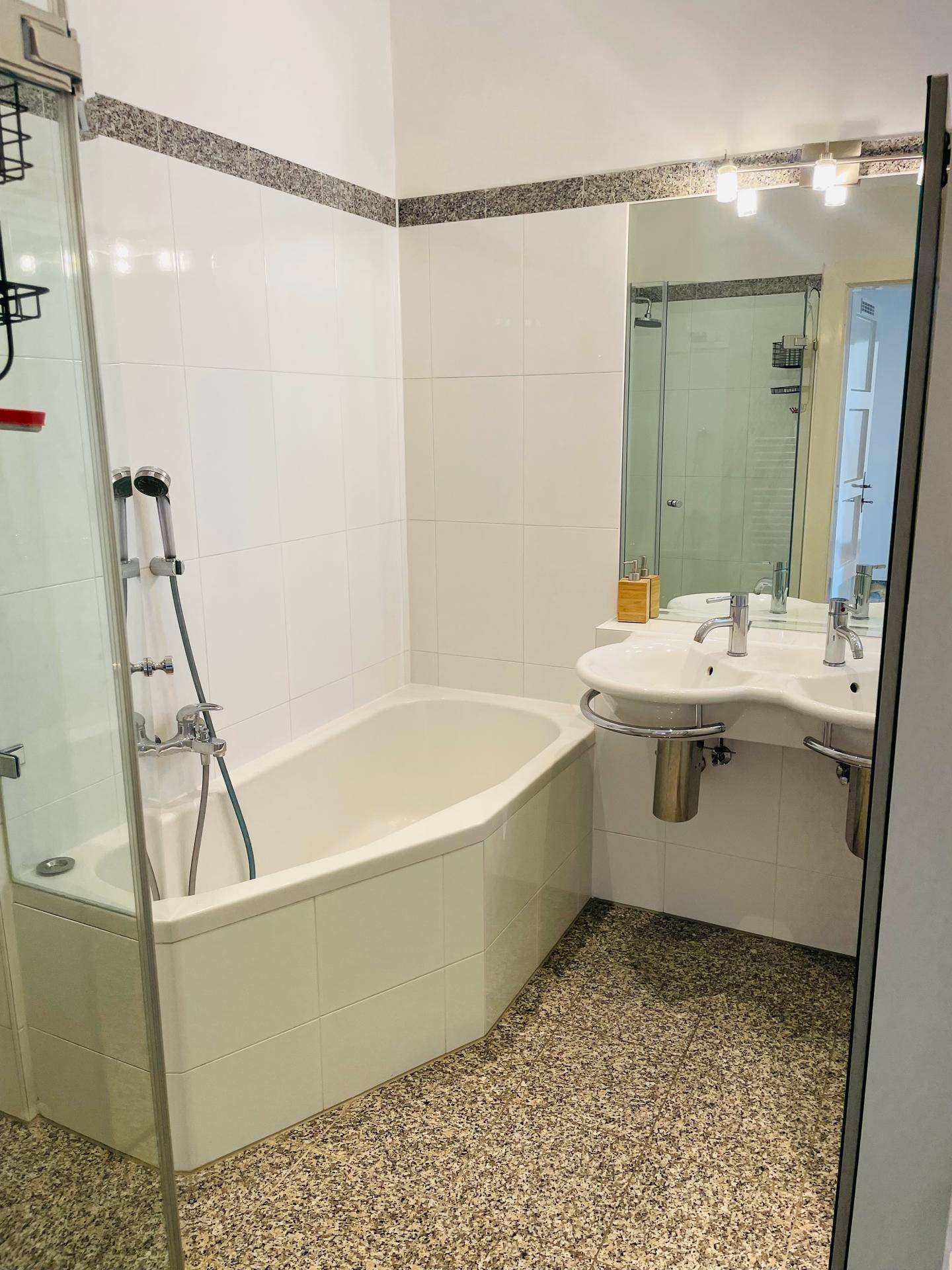 Badezimmer mit Eckbadewanne, integrierter Dusche und einem praktischen Doppelwaschbecken.