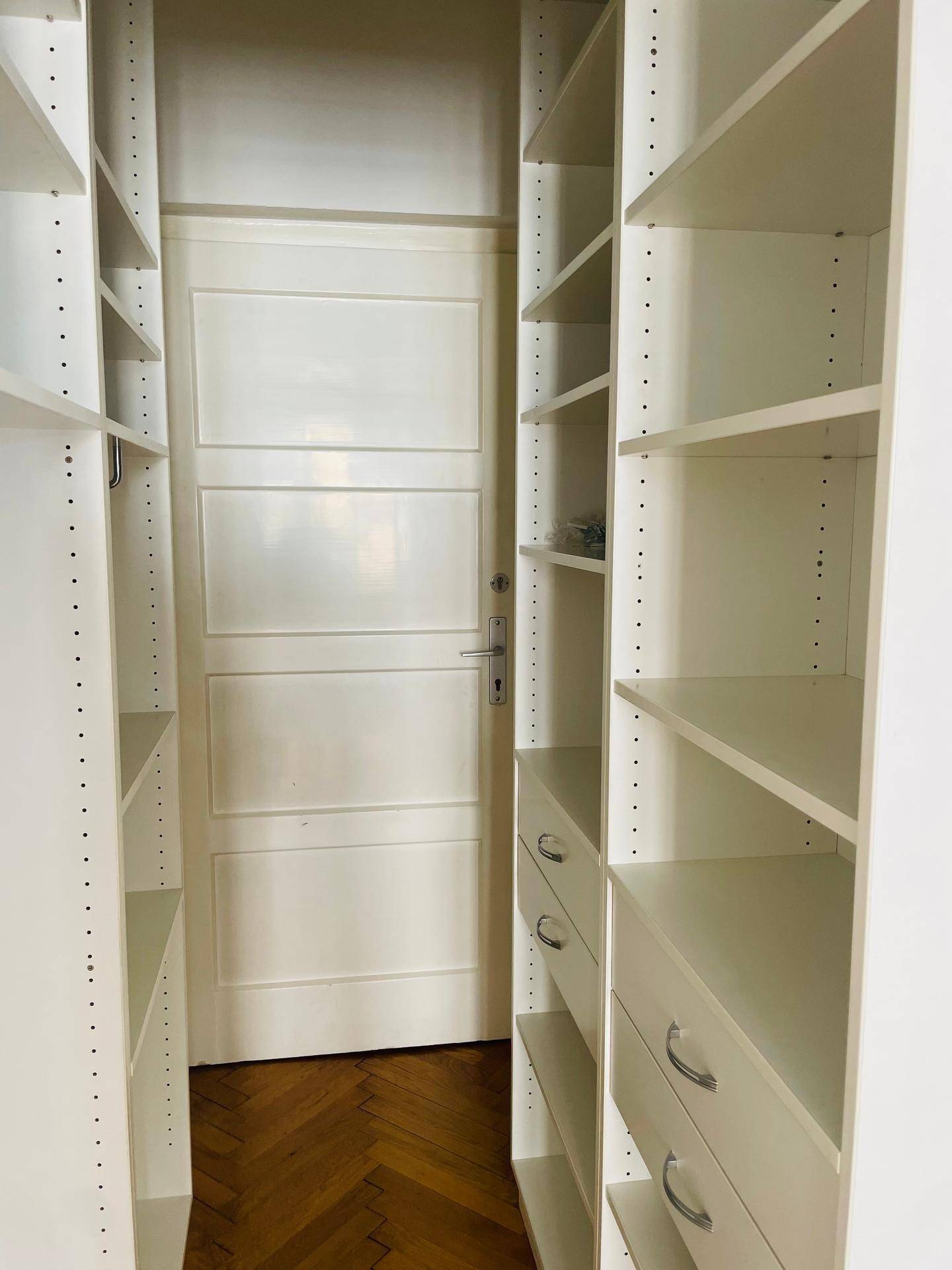 Gut organisierter begehbarer Kleiderschrank mit vielen Regalen und Schubladen für Stauraum.