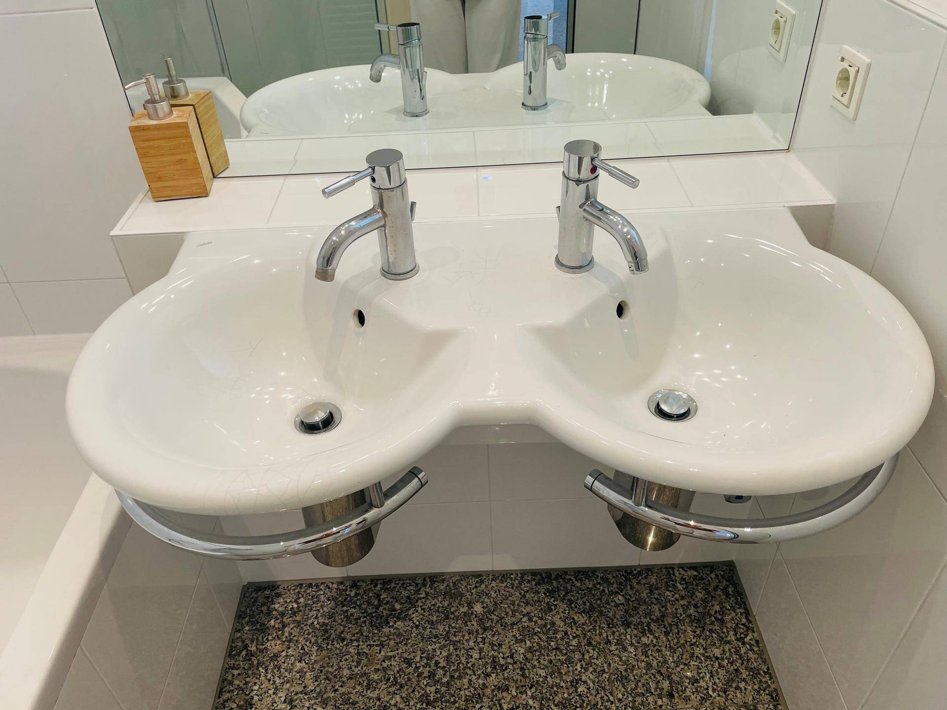 Nahaufnahme des Doppelwaschbeckens im Badezimmer mit modernen Armaturen und Spiegel.