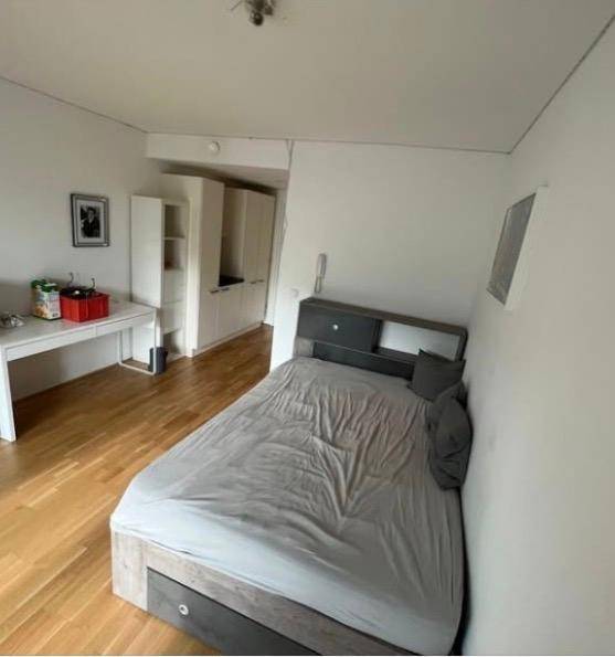 Schlafzimmer mit Holzboden, Bett, Schreibtisch und integrierten Schränken.