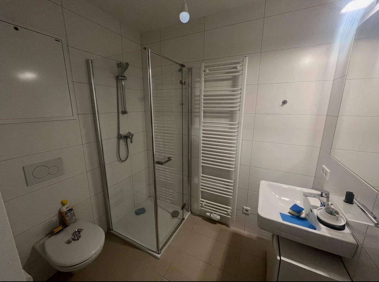 Modernes Badezimmer mit Duschkabine, wandhängendem WC, Waschbecken und Handtuchheizkörper.