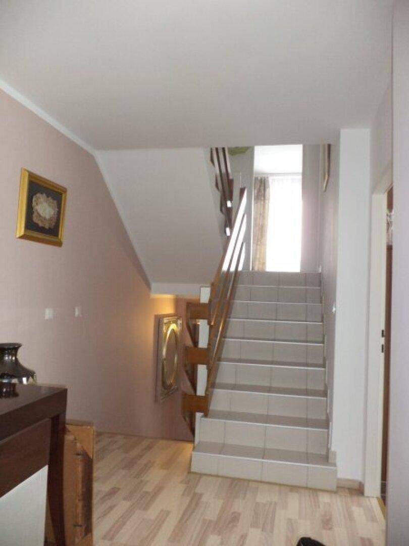 Heller Flur mit Treppe, die in die oberen Stockwerke führt, und Holzboden.