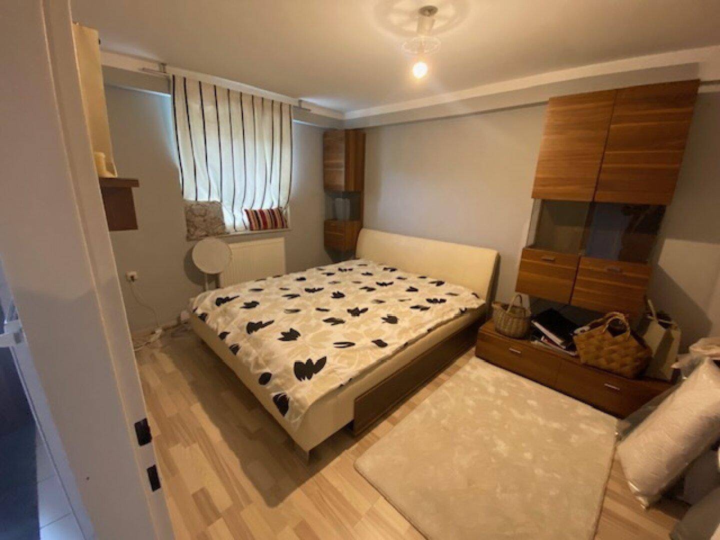 Gemütliches Schlafzimmer mit Holzboden, Doppelbett und Holzschränken an der Wand.