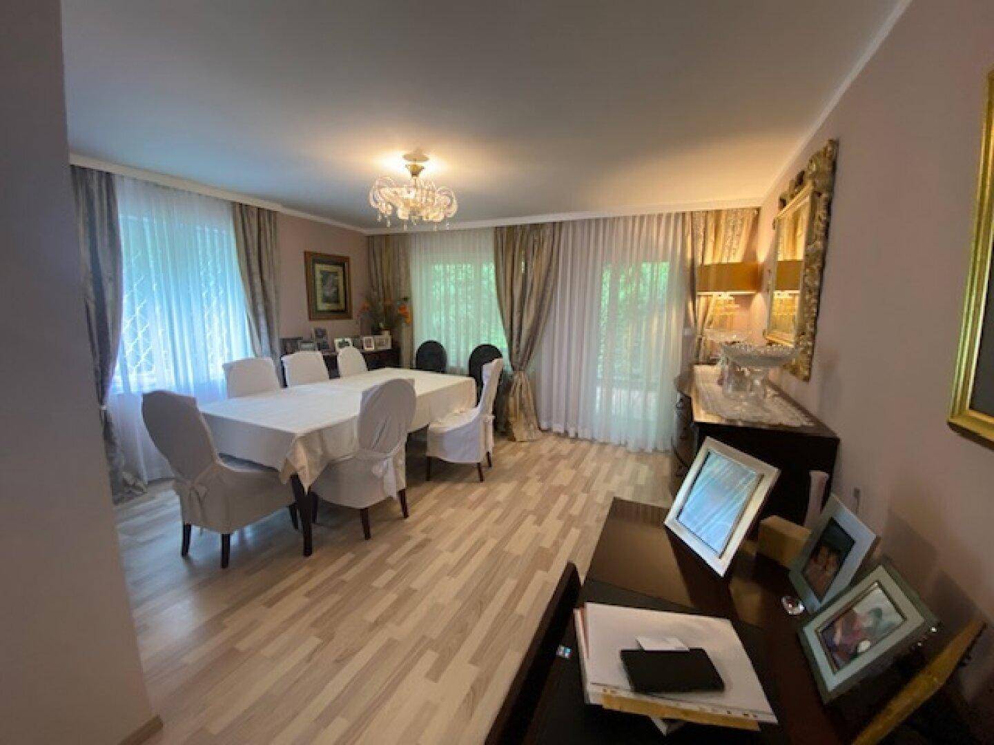 Klassisch eingerichtetes Esszimmer mit hellem Boden, großem Tisch und dekorativen Elementen.