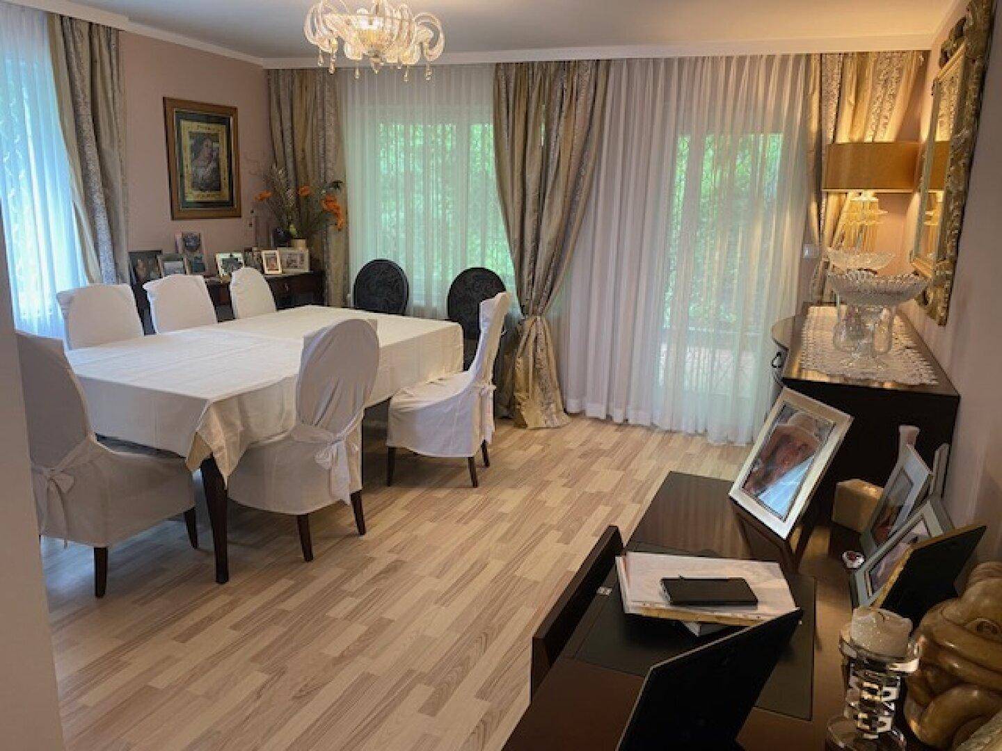 Elegantes Esszimmer mit großem Esstisch, Stühlen und einem Kronleuchter an der Decke.