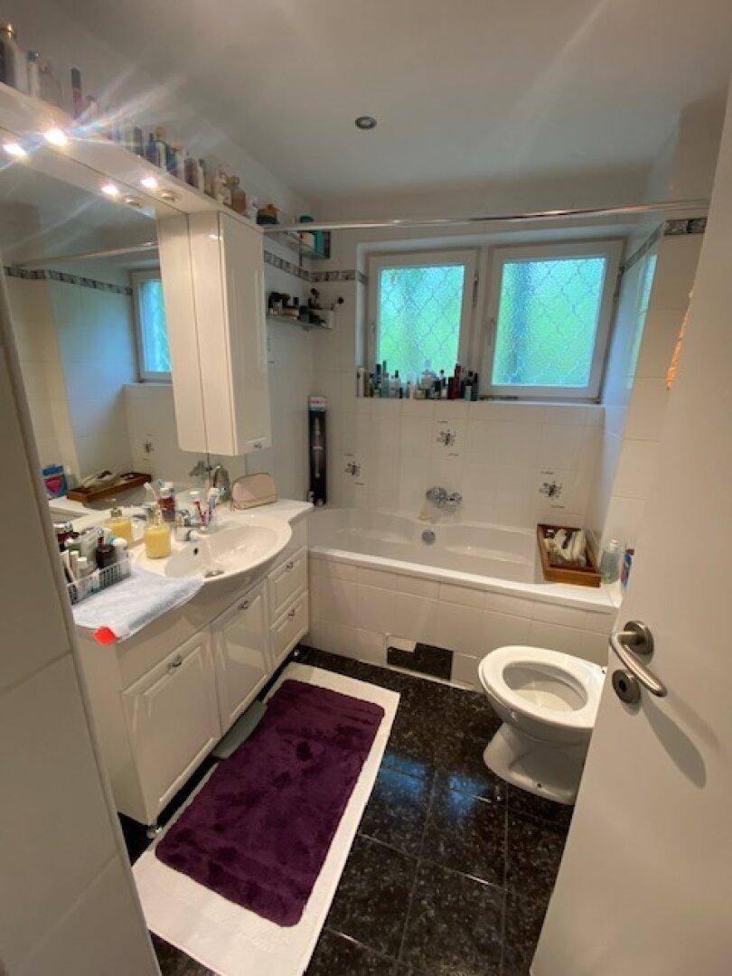 Badezimmer mit Badewanne, Waschbecken mit Unterschrank und Fenster.