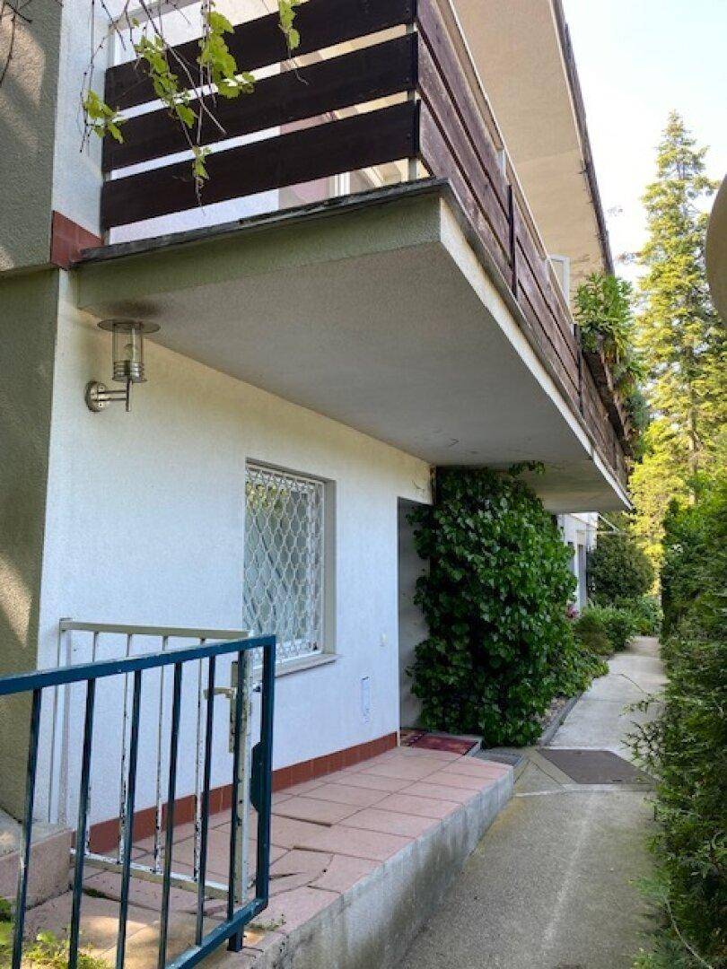 Außenansicht des Hauses mit einem Weg, umgeben von Grün und einem Balkon im oberen Stockwerk.