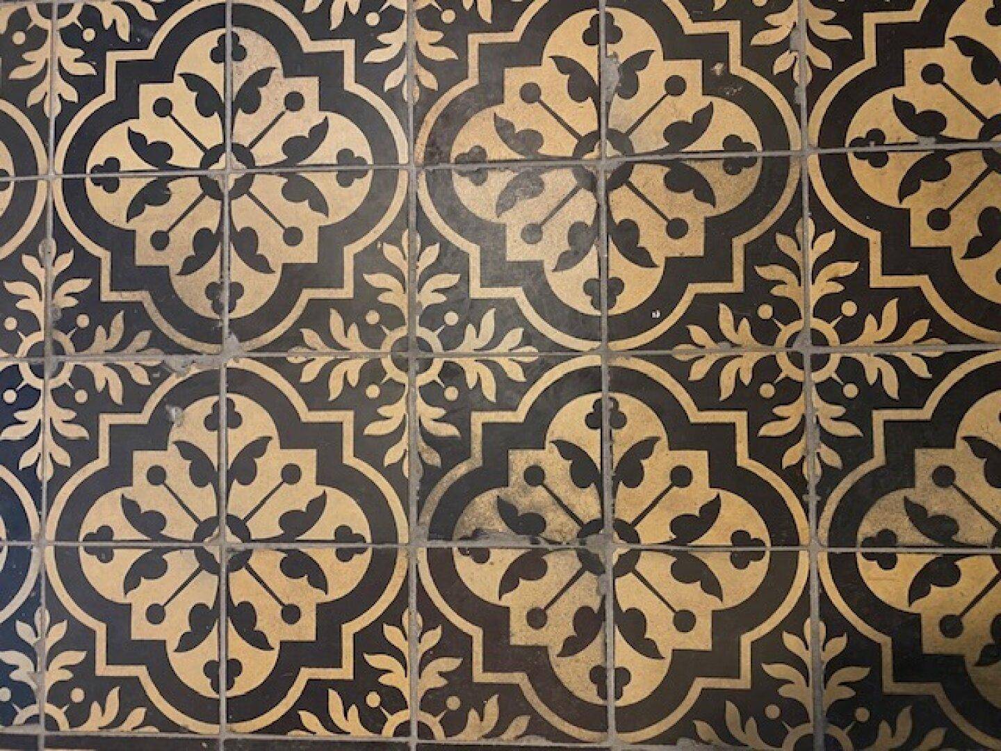 Detailaufnahme von kunstvollen, gemusterten Bodenfliesen in Schwarz und Beige, die Eleganz verleihen.