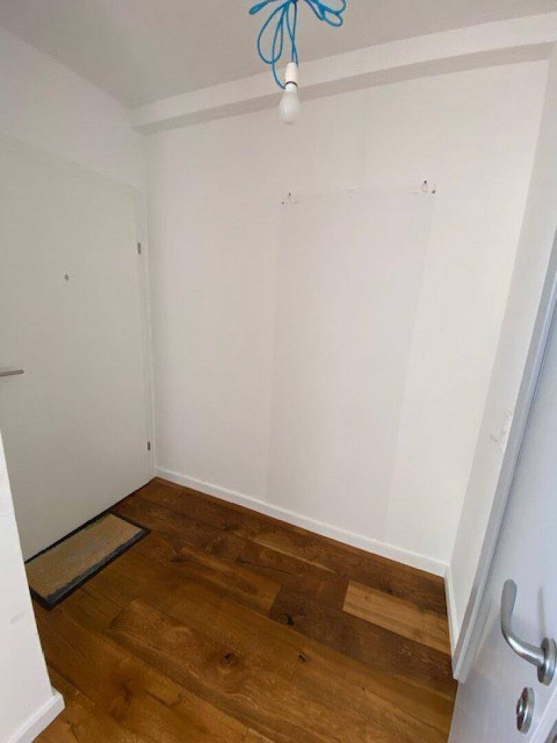 Kleiner, heller Eingangsbereich mit Holzboden und weiß gestrichenen Wänden, einladend gestaltet.