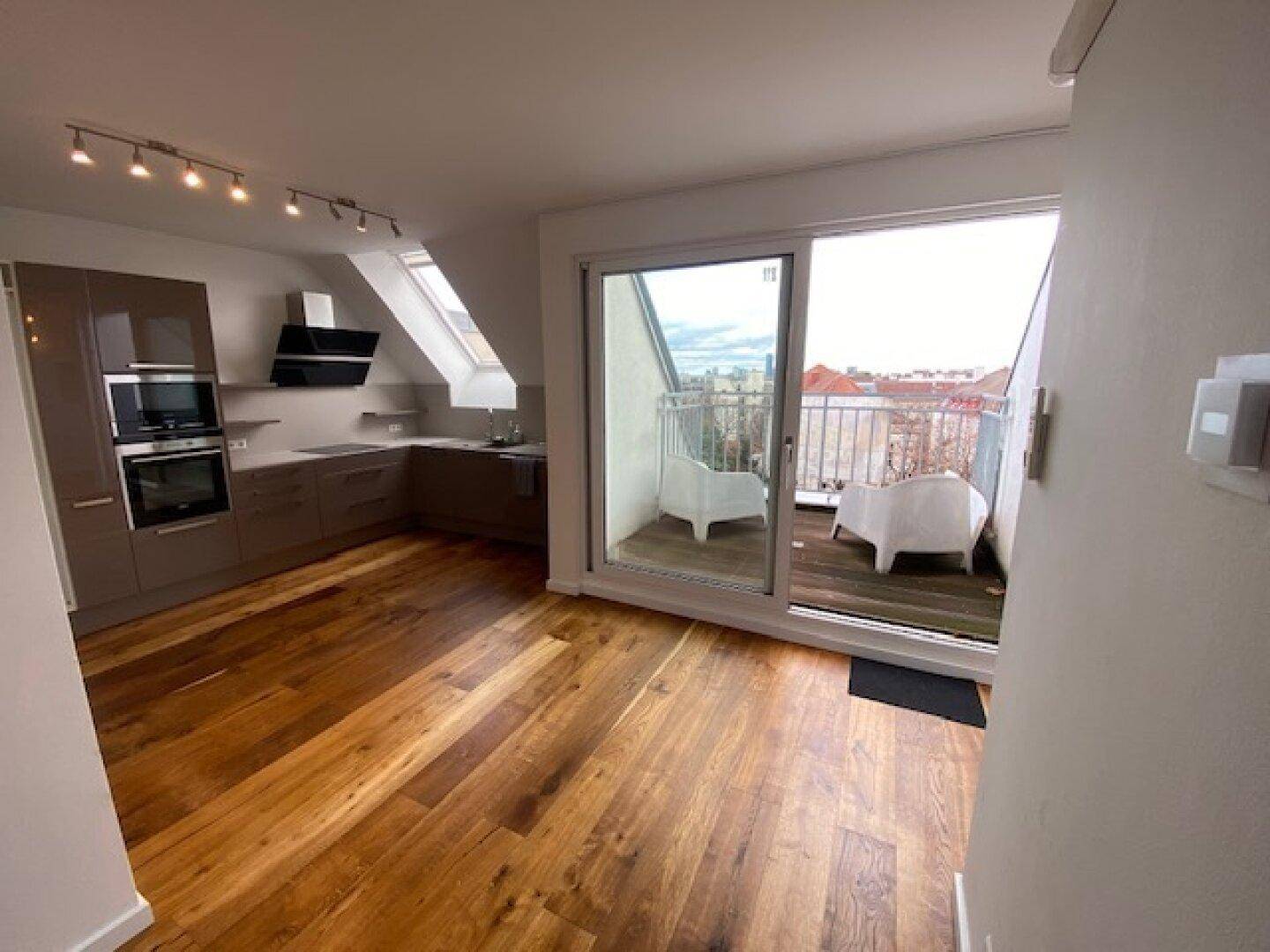 Helle Küche mit modernen Geräten und direktem Zugang zu einem möblierten Balkon.