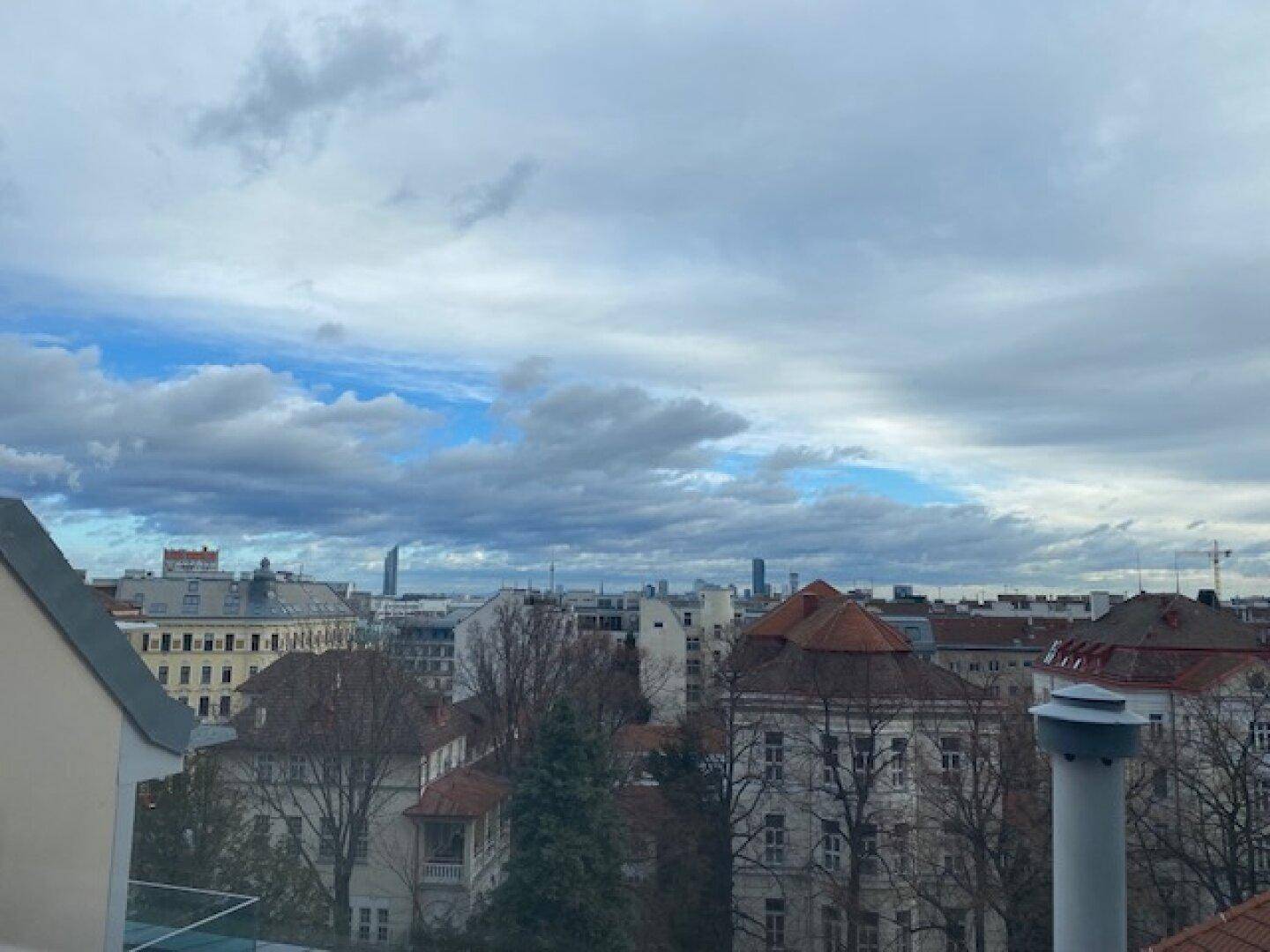 Weitblick über die Dächer der Stadt mit bewölktem Himmel und urbaner Architektur.