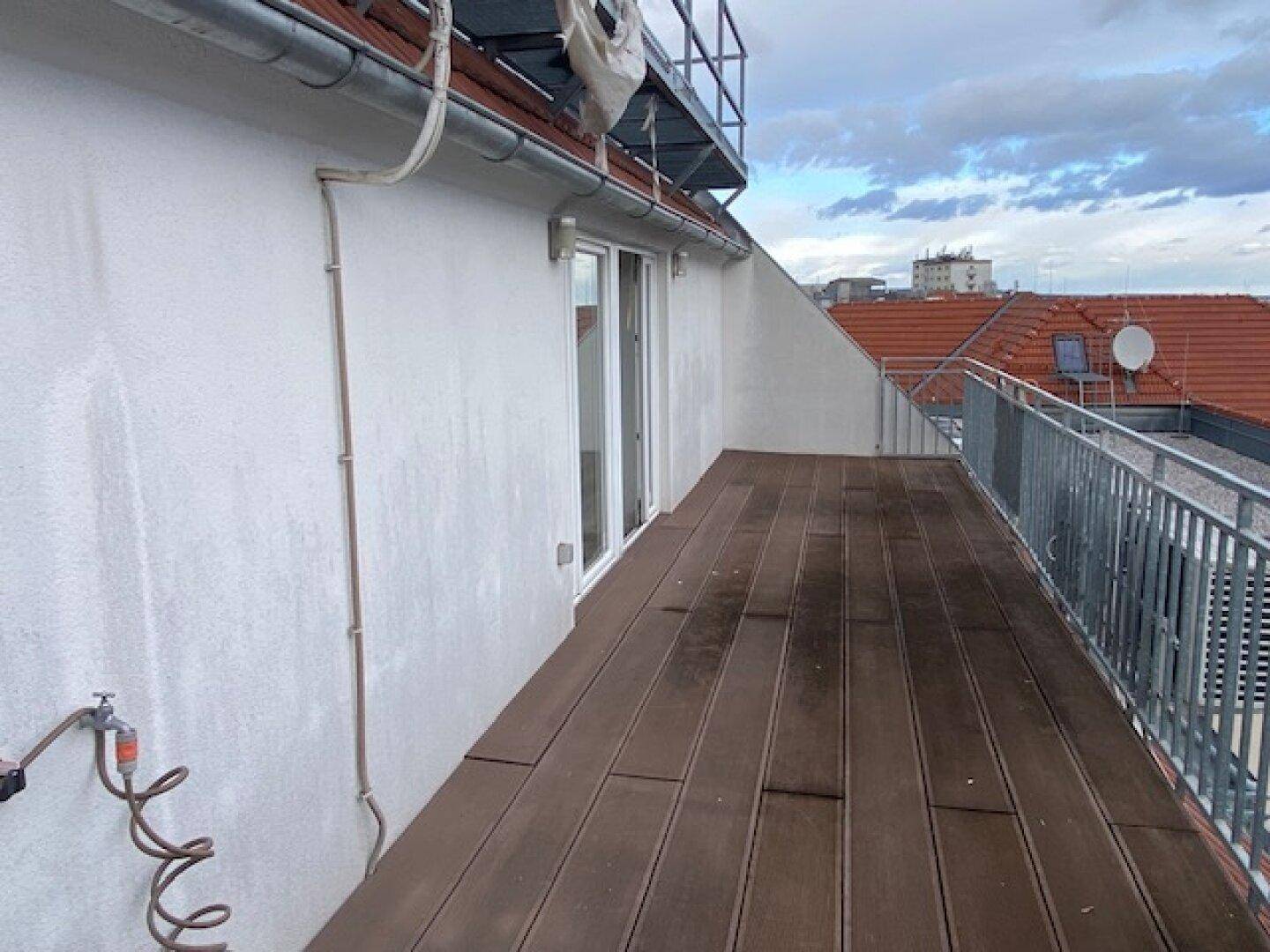 Geräumige Dachterrasse mit Holzboden und Metallgeländer, ideal für Entspannung im Freien.
