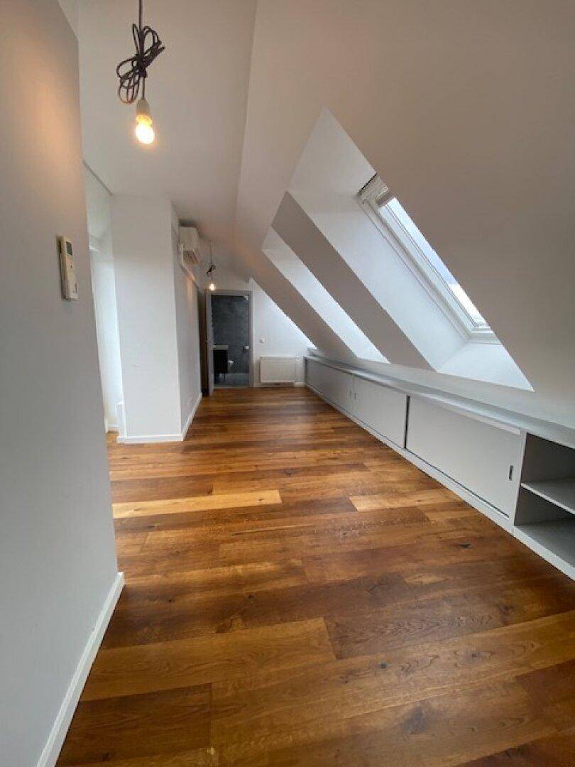 Geräumiger Dachgeschossbereich mit Holzboden, Dachfenstern und integrierten Stauschränken.