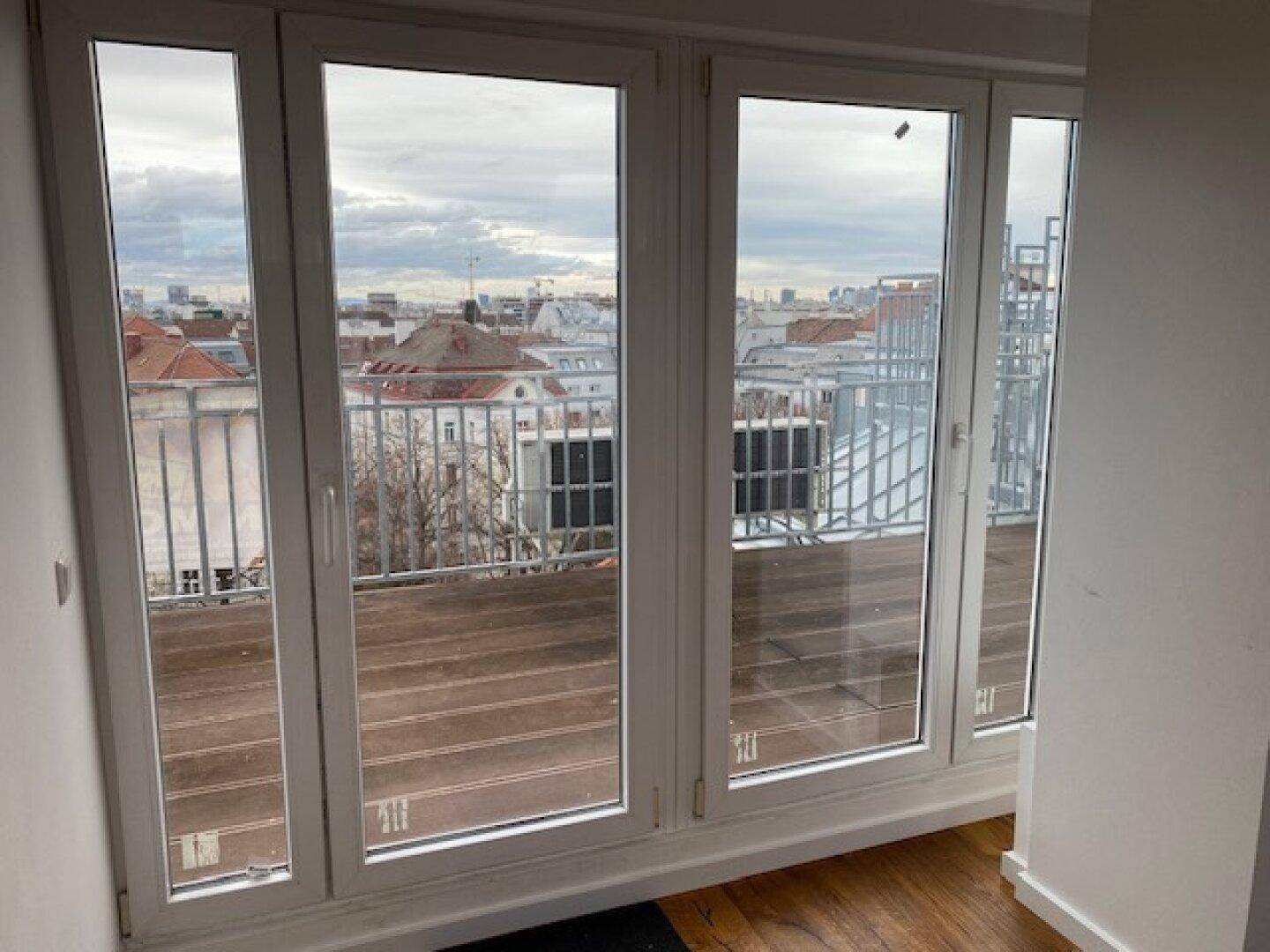 Große Glasschiebetüren bieten Zugang zum Balkon und einen weiten Blick über die Stadt.