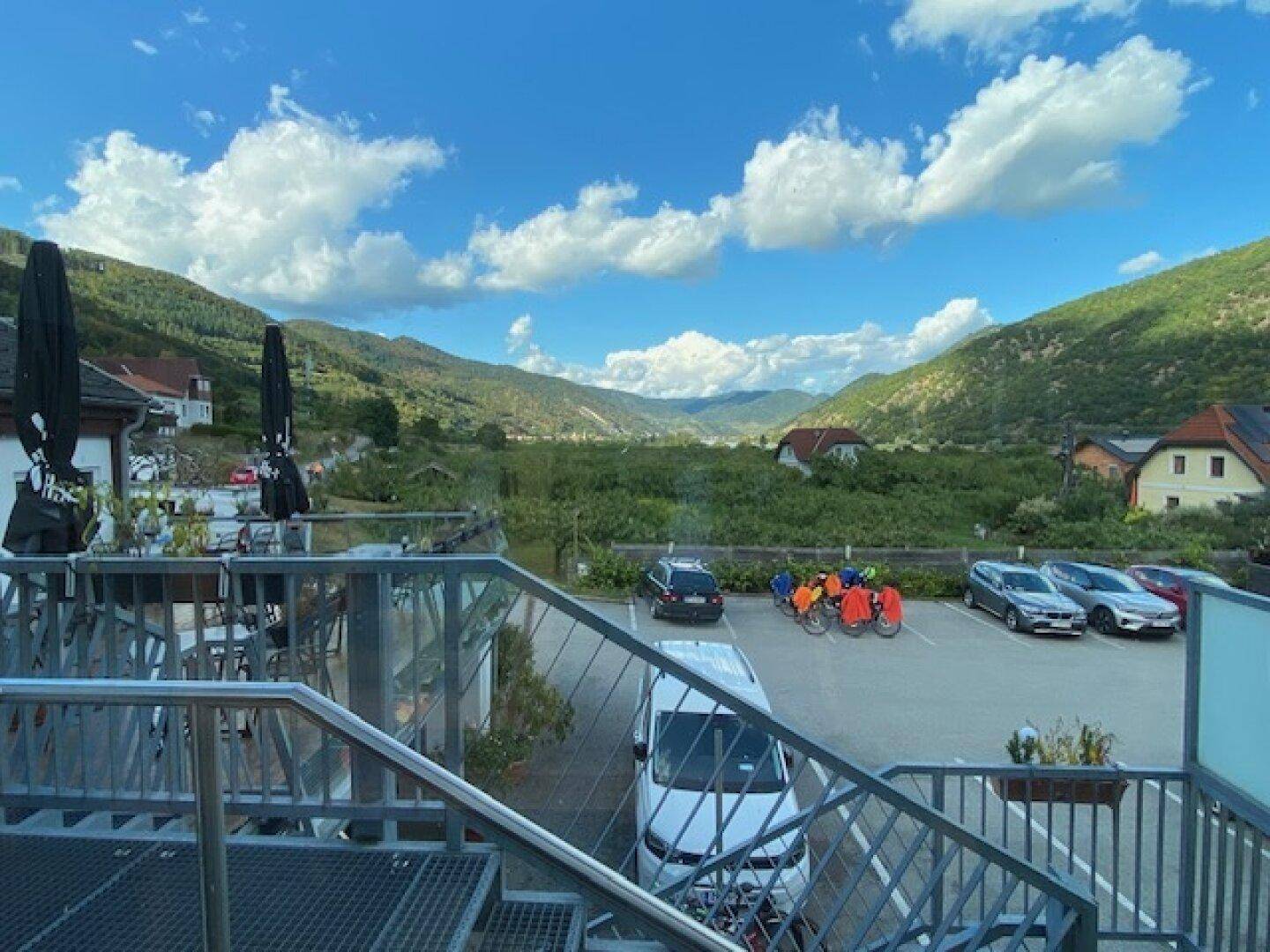 Terrasse mit Metallgeländer und Blick auf den Parkplatz sowie die malerische Berglandschaft.