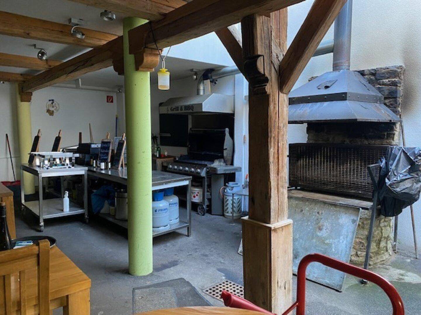 Großer Grill- und Vorbereitungsbereich mit professioneller Ausstattung und Holzbalken.