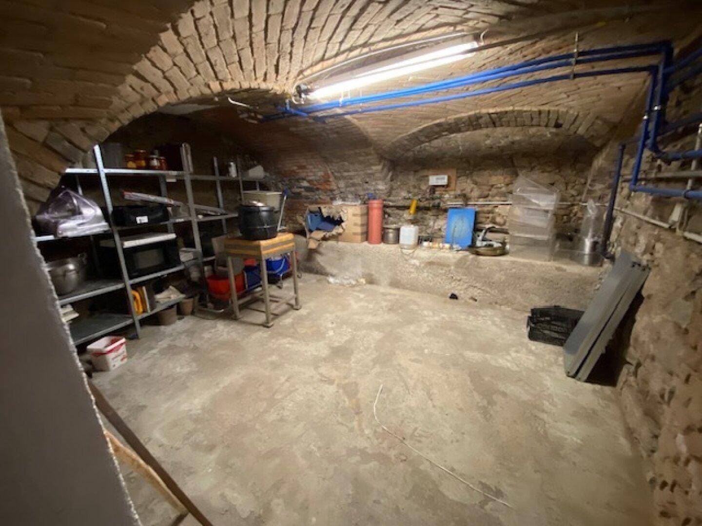 Historischer Kellerraum mit Ziegelgewölbedecke und Lagerregalen, ideal für Vorräte.