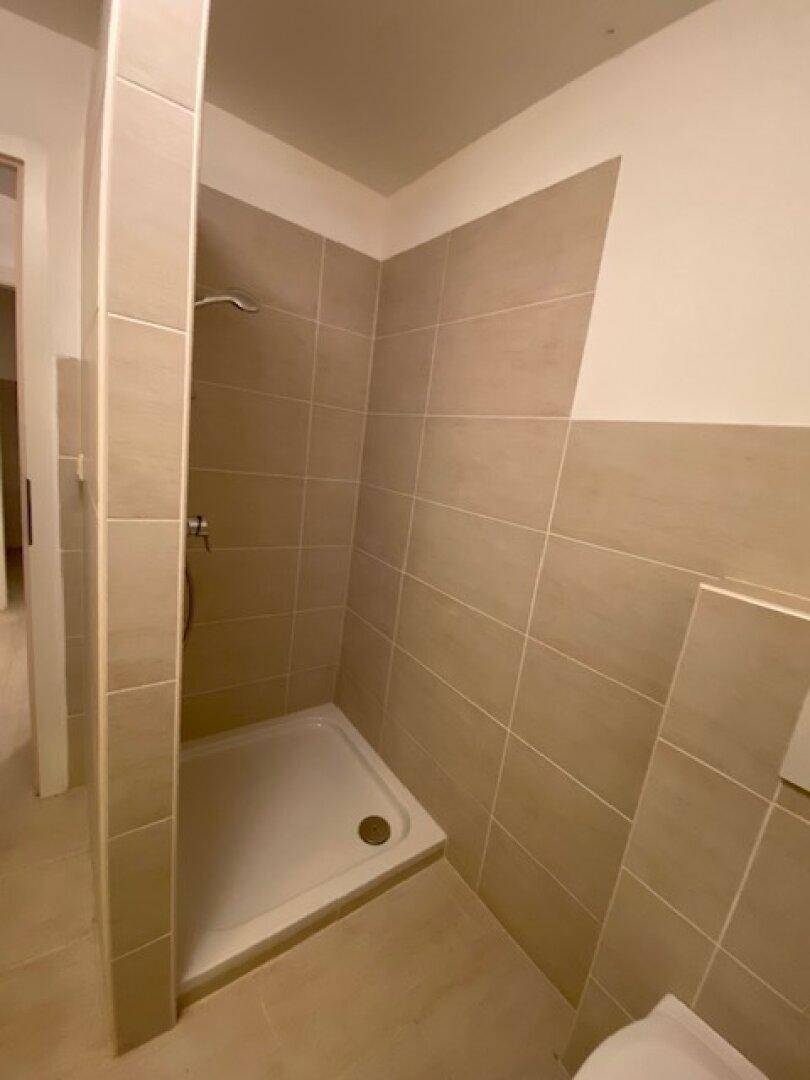 Modern geflieste Duschkabine in beigen Farbtönen, mit minimalistischem Design und sauberer Ausführung.