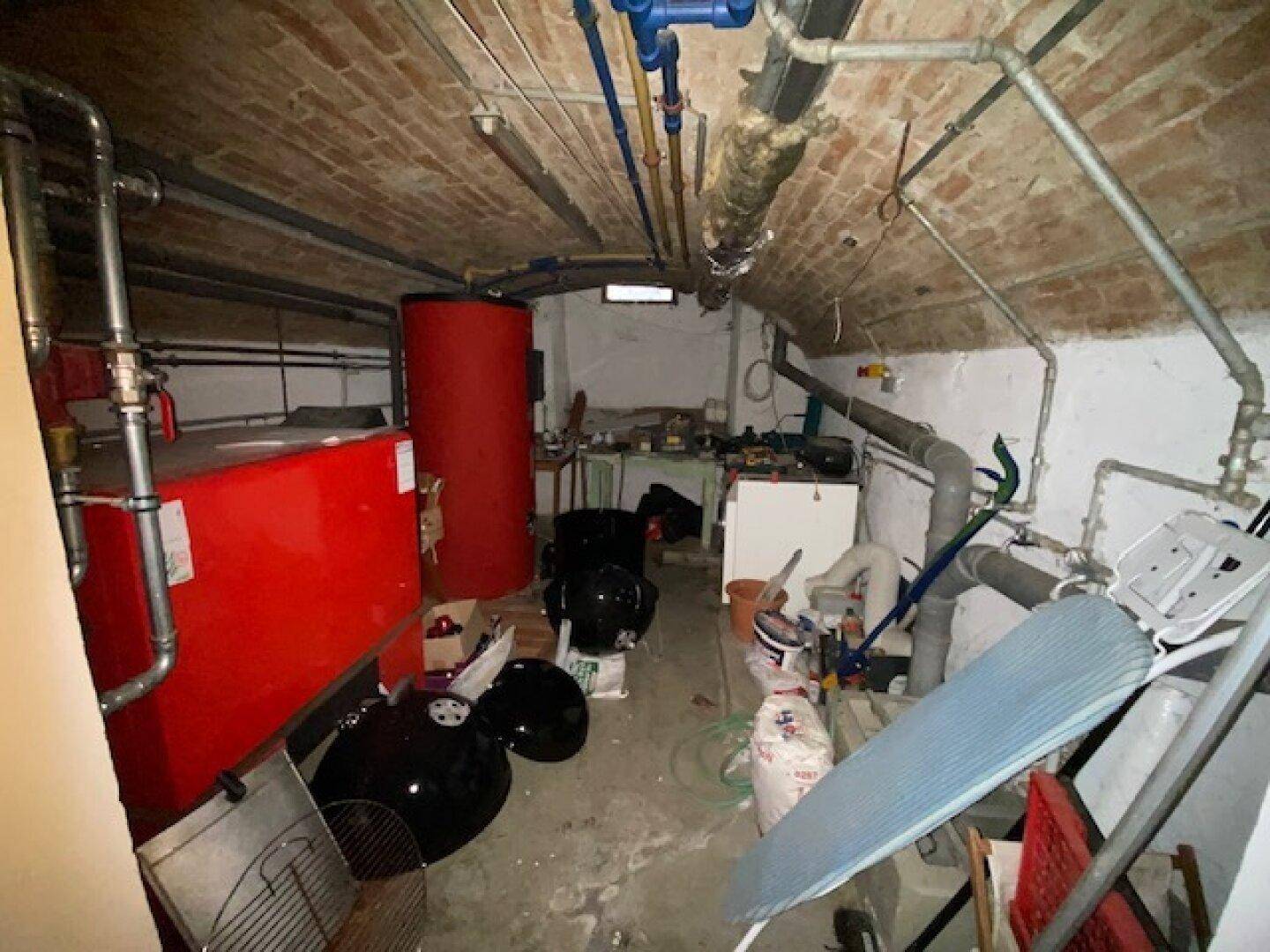 Heizungsraum im Keller mit großen Warmwasserspeichern und sichtbaren Rohrleitungen.