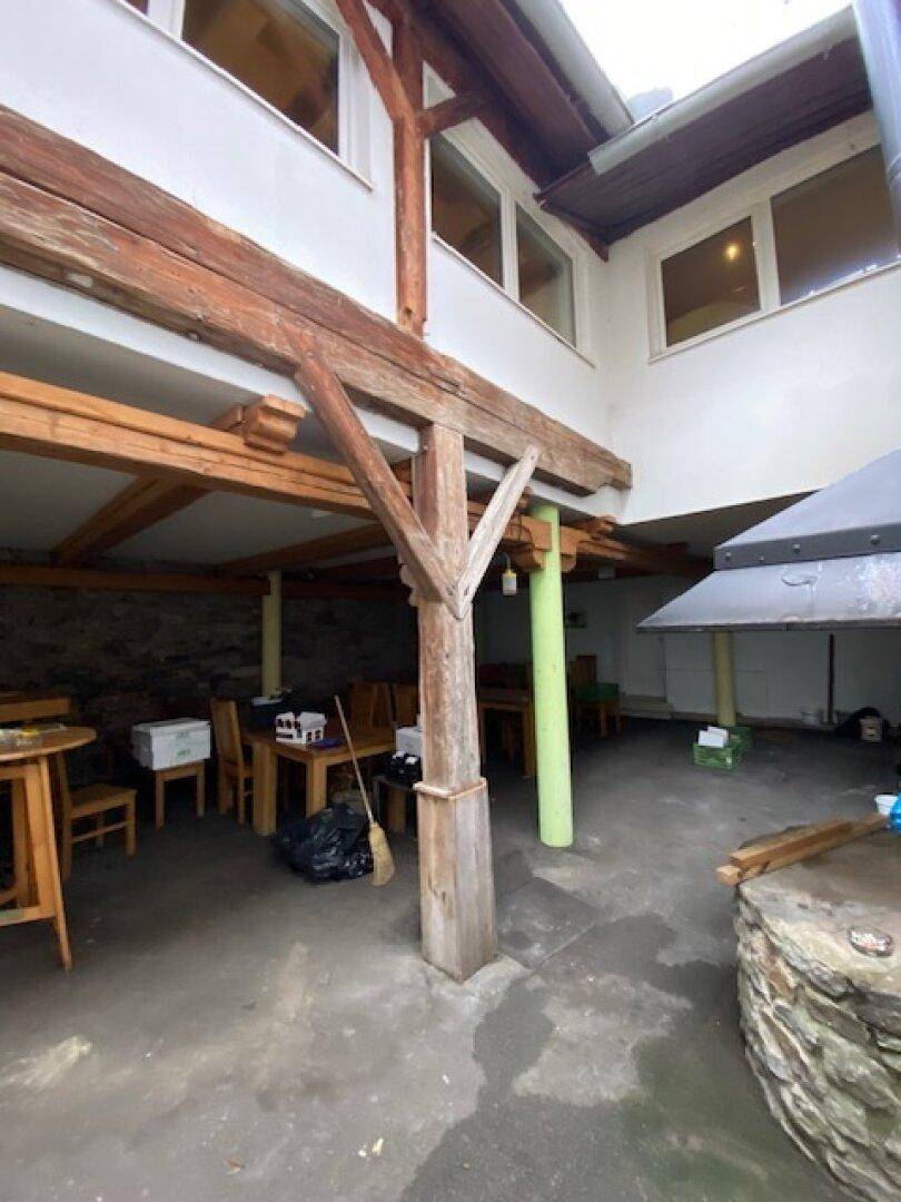 Überdachter Außenbereich mit Holzbalken und Steinsäulen, ideal für Mahlzeiten im Freien.