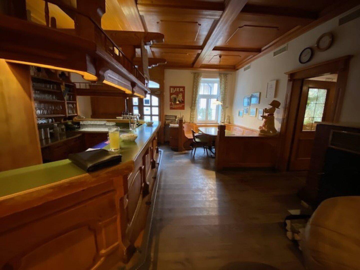Traditioneller Barbereich mit langer Holztheke, Holzbalkendecke und gemütlichen Sitzgelegenheiten.