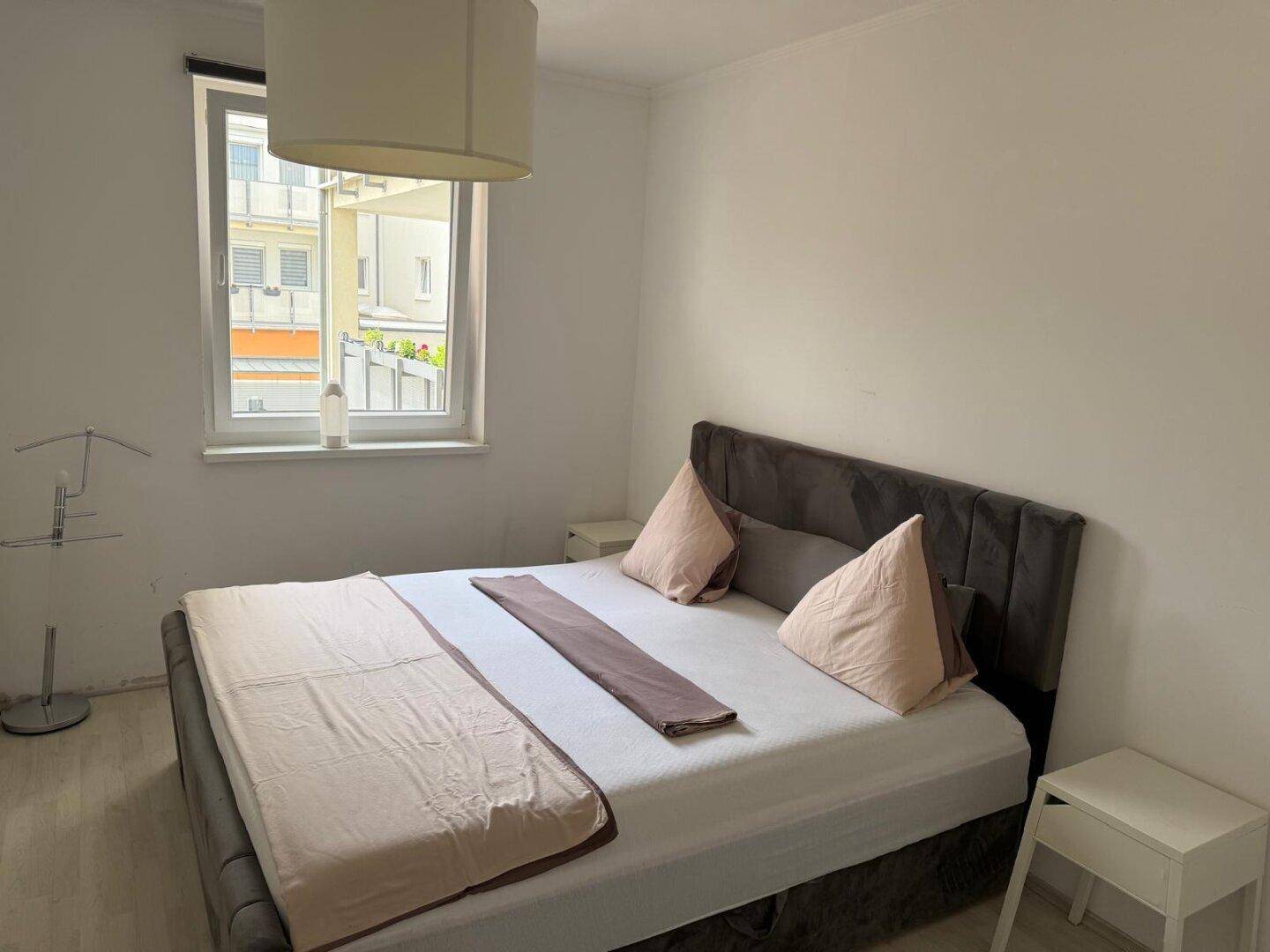 Gemütliches Schlafzimmer mit Doppelbett, Nachttischen und großem Fenster.
