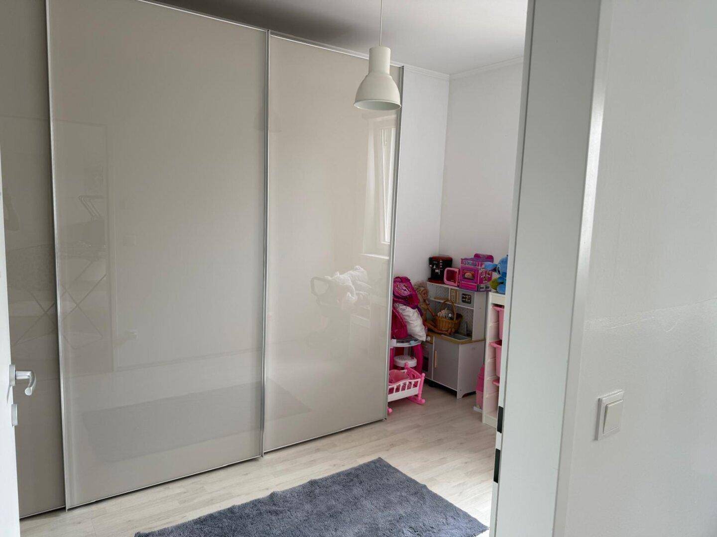 Schlafzimmer mit großem Schiebetürenschrank und Spielzeug in der Ecke.