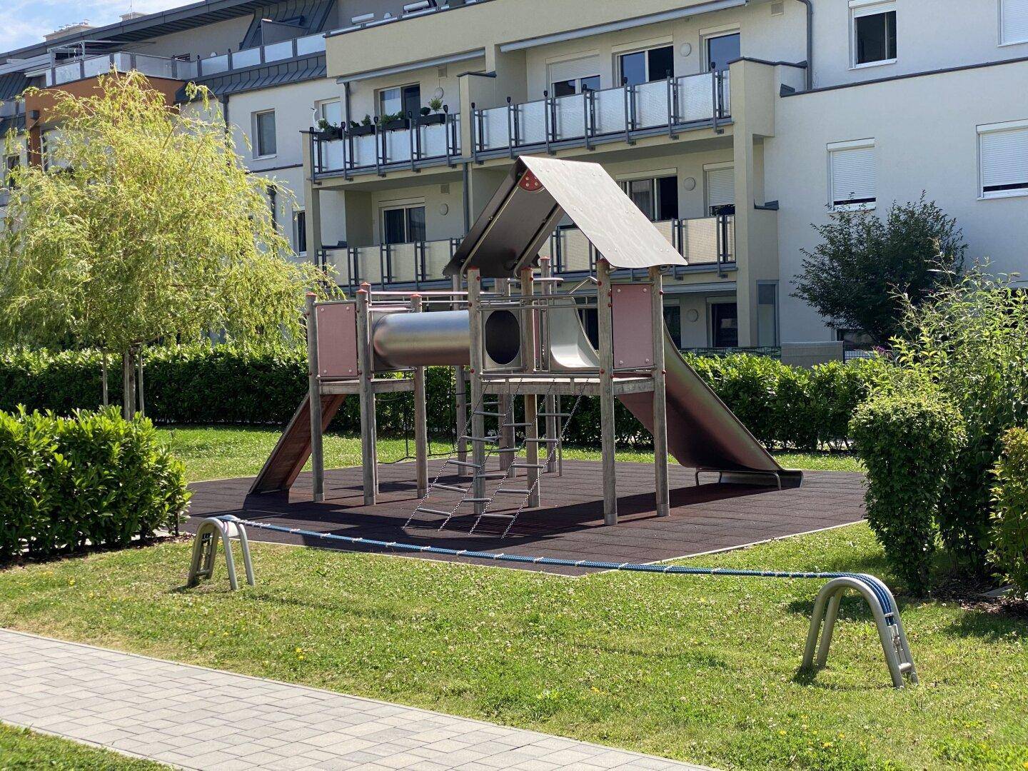 Großer Spielturm mit Rutschen und Kletterelementen auf einem Spielplatz.
