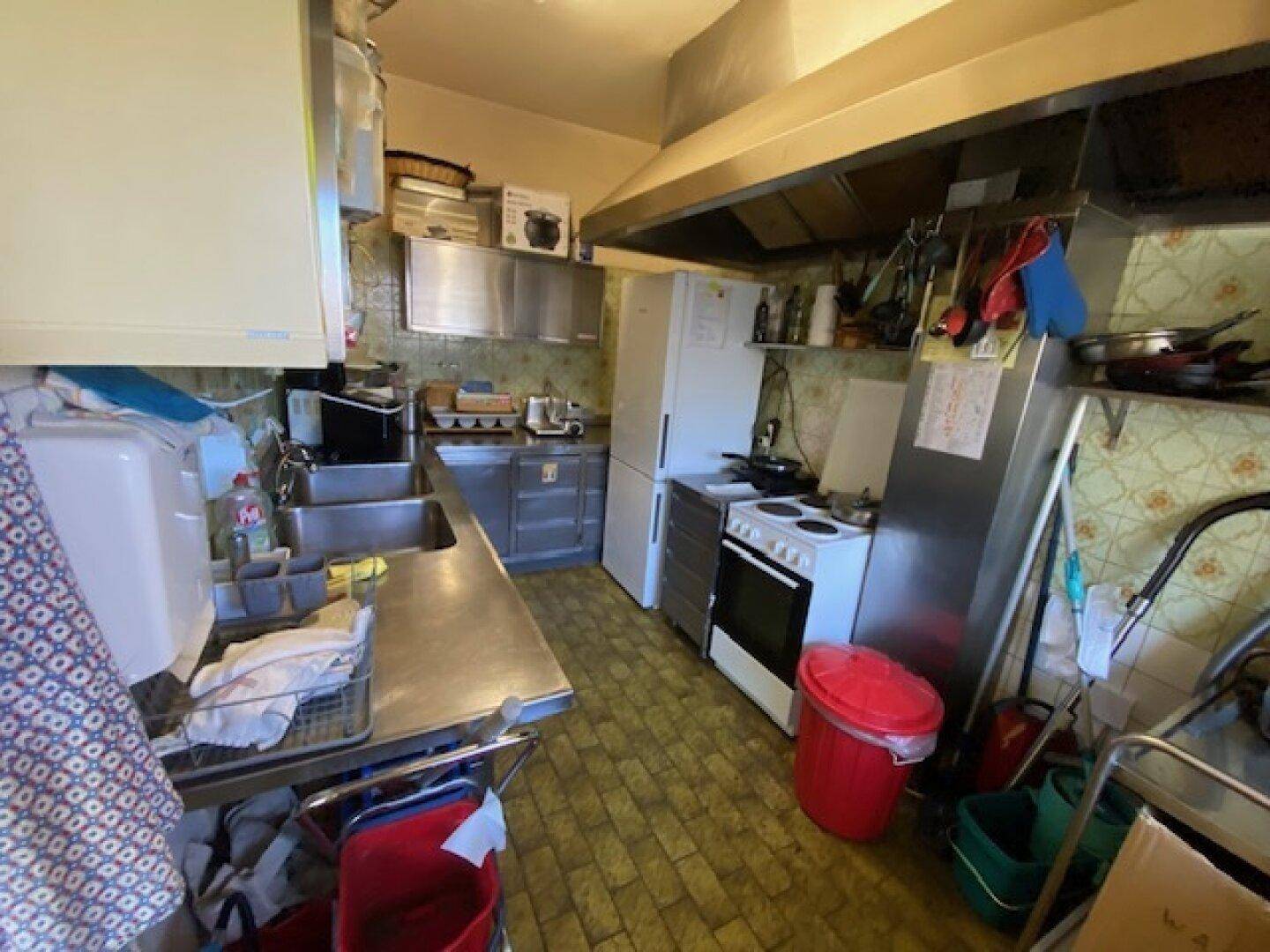 Gut ausgestattete Küche mit Arbeitsflächen aus Edelstahl, Herd und Kühlschrank.
