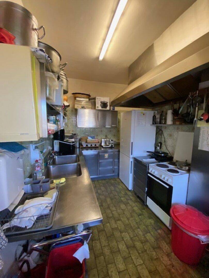 Funktionale Küche mit Edelstahlspüle, Herd und Kühlschrank, bereit für den Gastronomiebetrieb.