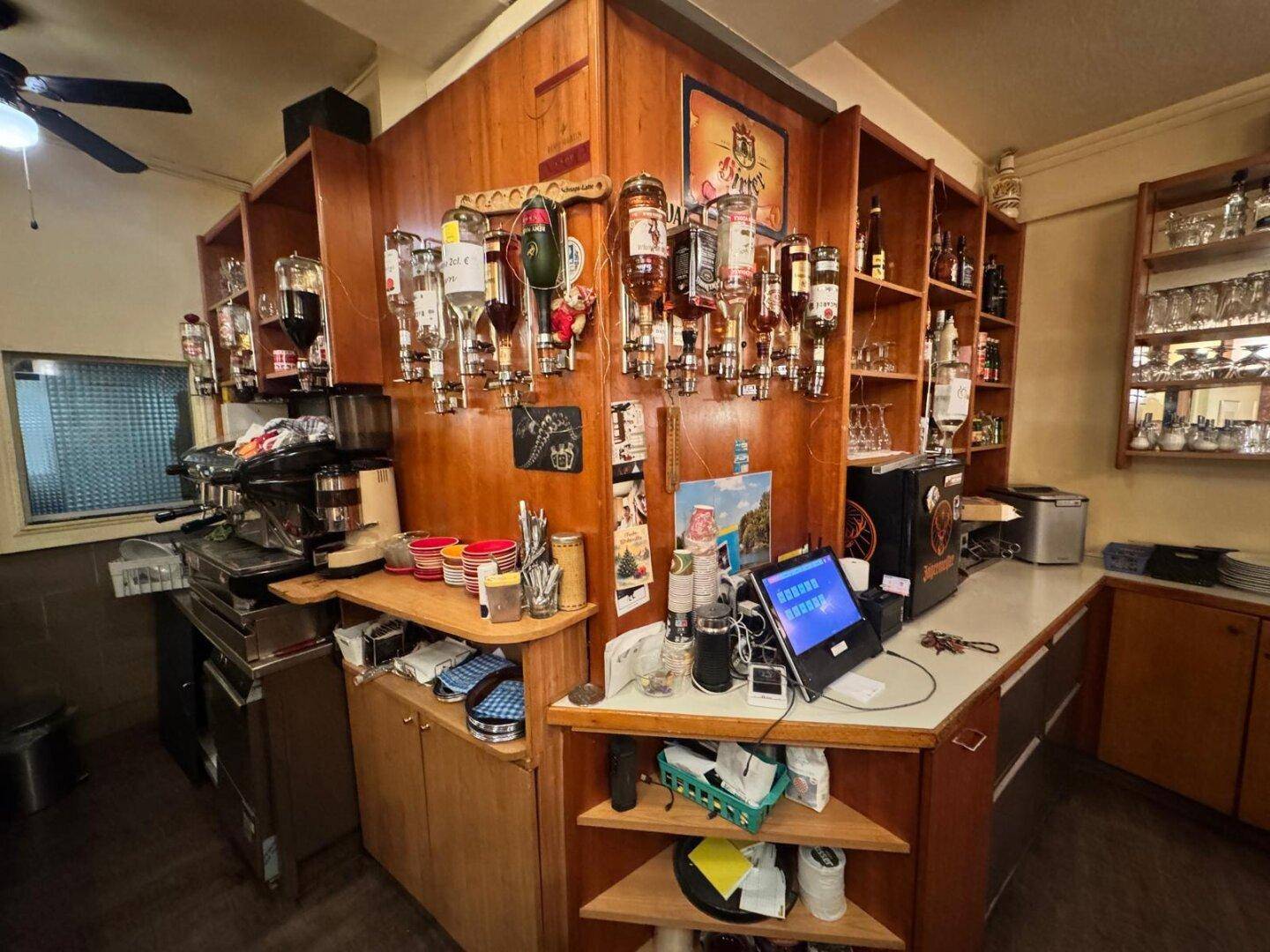Detailansicht des Barbereichs mit zahlreichen Flaschen, Kaffeemaschine und professioneller Ausstattung.