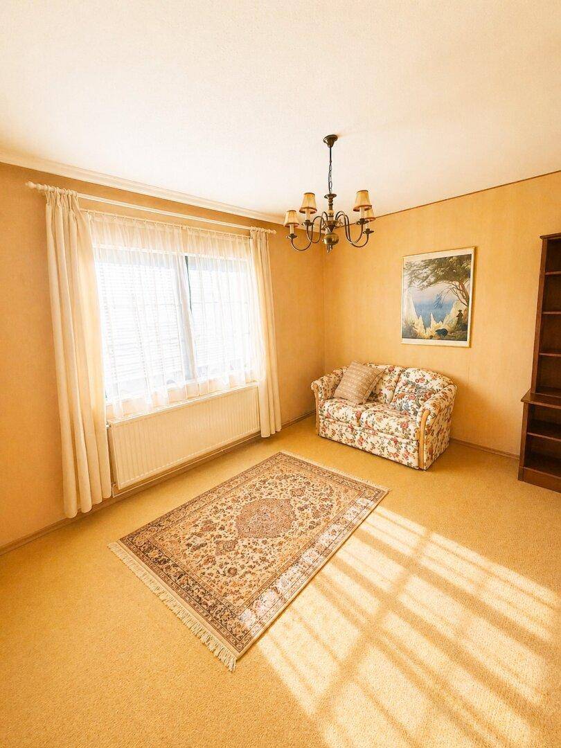 Gemütlicher Raum mit Teppichboden, einem kleinen Sofa und einem Fenster für natürliches Licht.