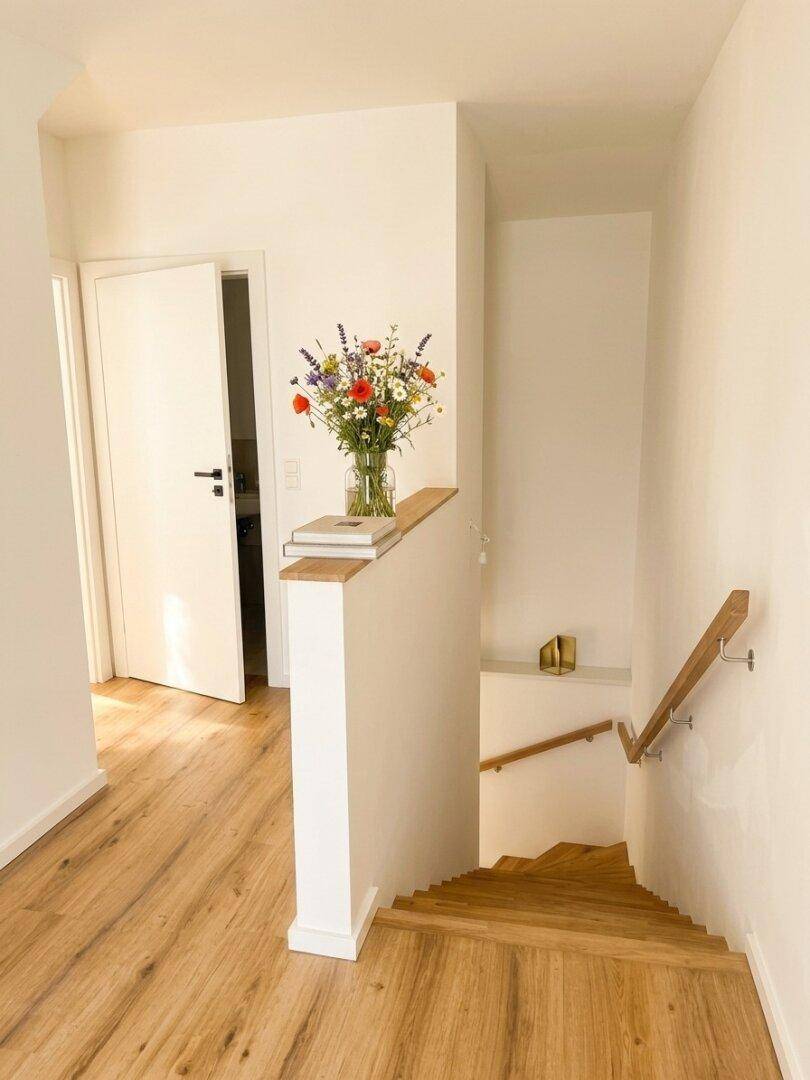 Heller Flur mit Holztreppe und Holzboden, der zu den oberen Etagen führt.