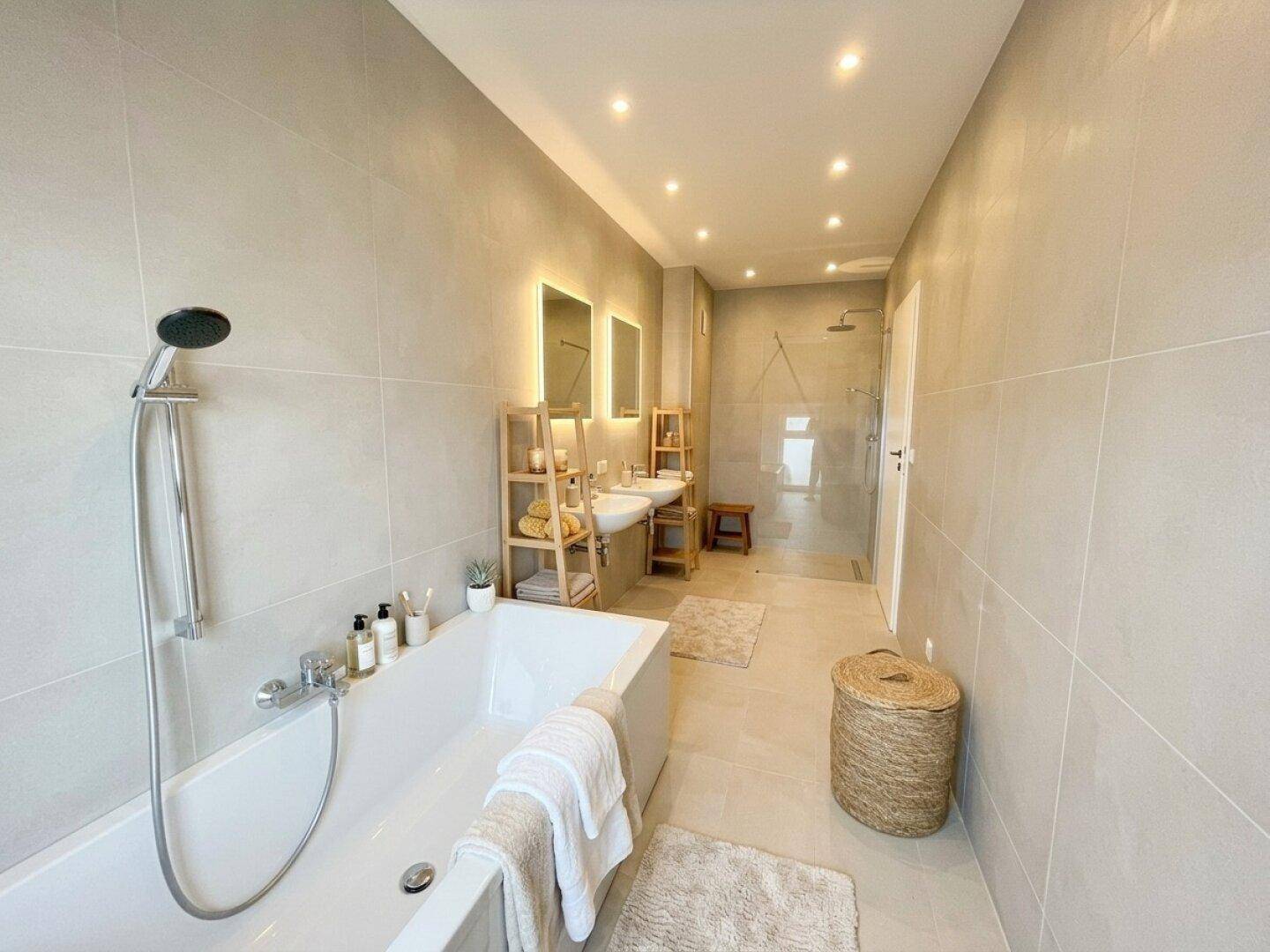 Geräumiges Badezimmer mit Badewanne, Dusche, Doppelwaschbecken und modernen Fliesen.